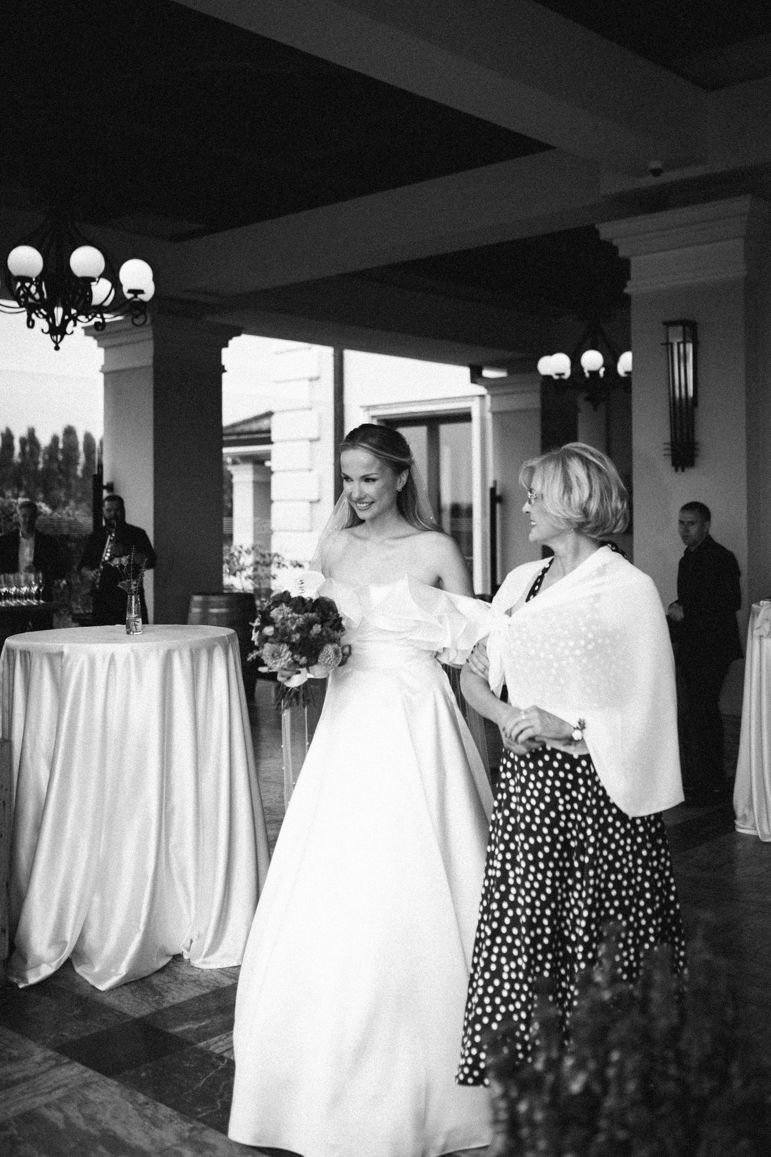 Black and white wedding photo showing a bride in a classic strapless gown with an elegant companion in polka dots.