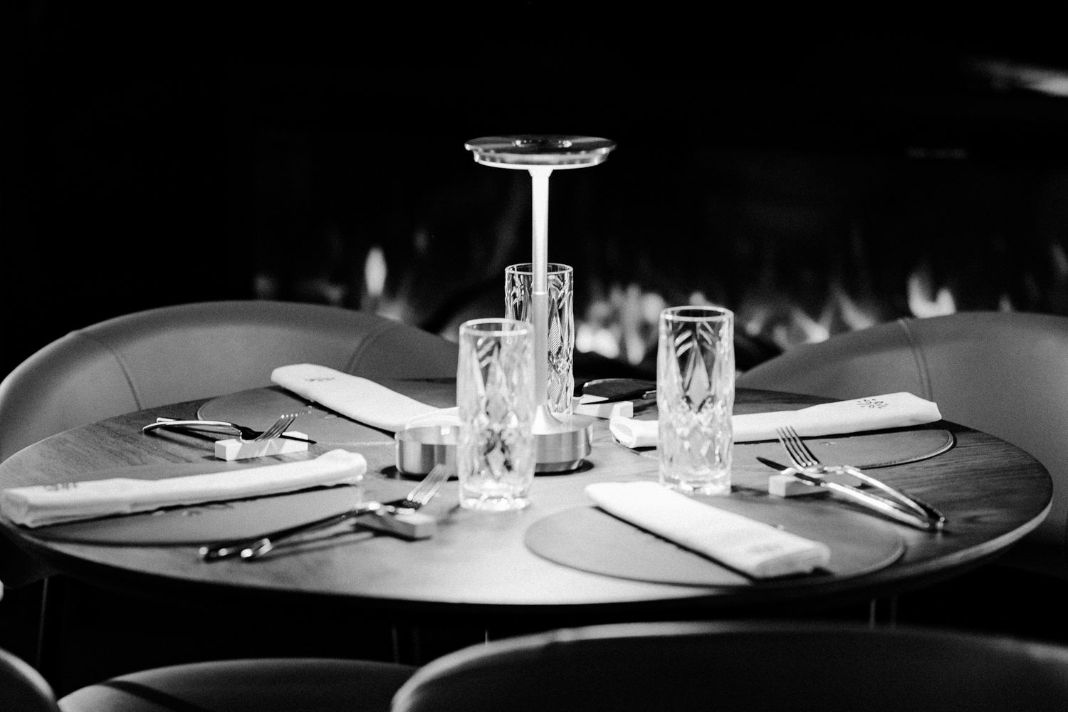 Place settings on round tables in a dimly lit restaurant.