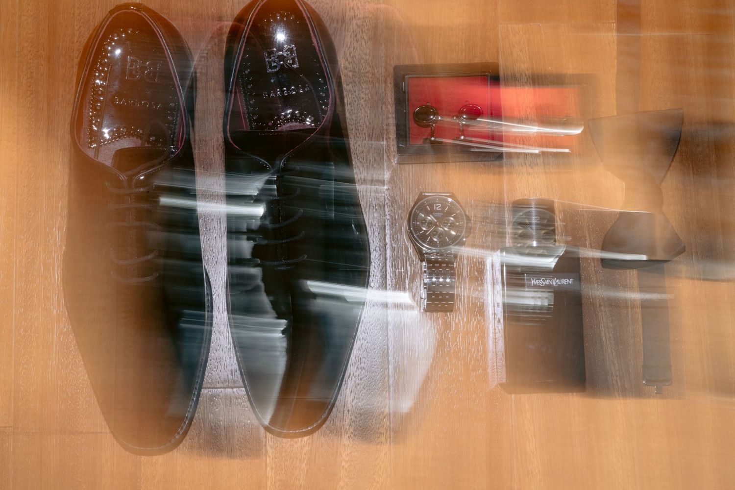 Blurry artistic photograph of dark leather dress shoes and other objects through frosted glass.
