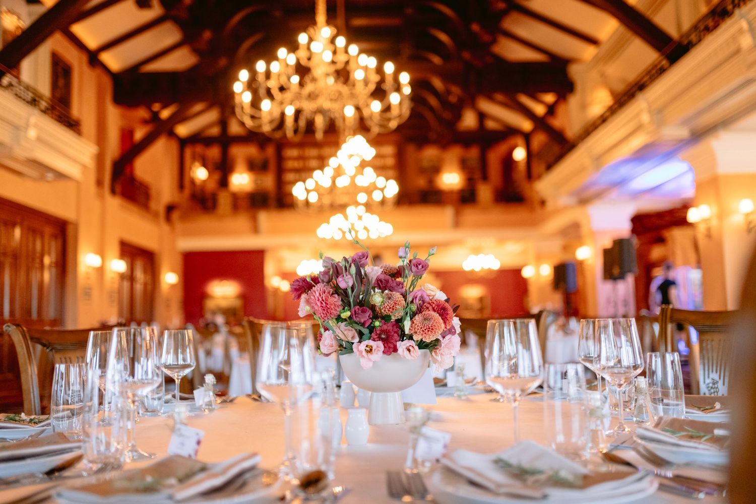 Grand reception hall with crystal chandeliers and elegant table settings for a wedding celebration.