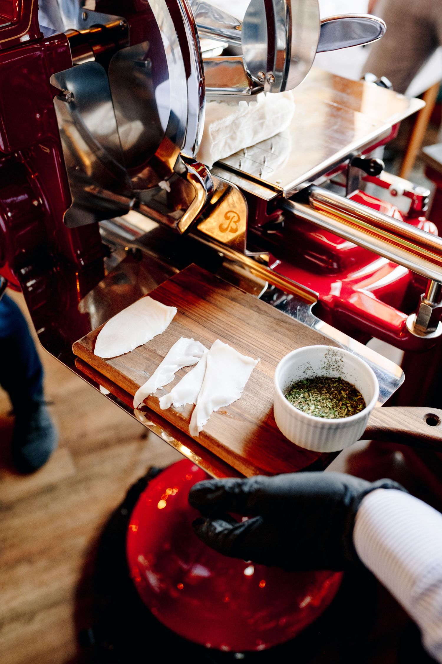A series of images showing someone grinding and preparing tea leaves on a wooden table with red ceramic accessories.