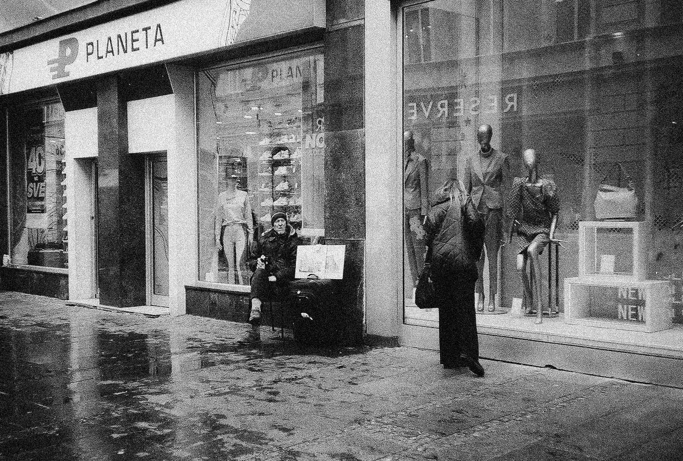 Vintage black and white photograph of a storefront called Planeta with a mannequin in the window on a rainy day.