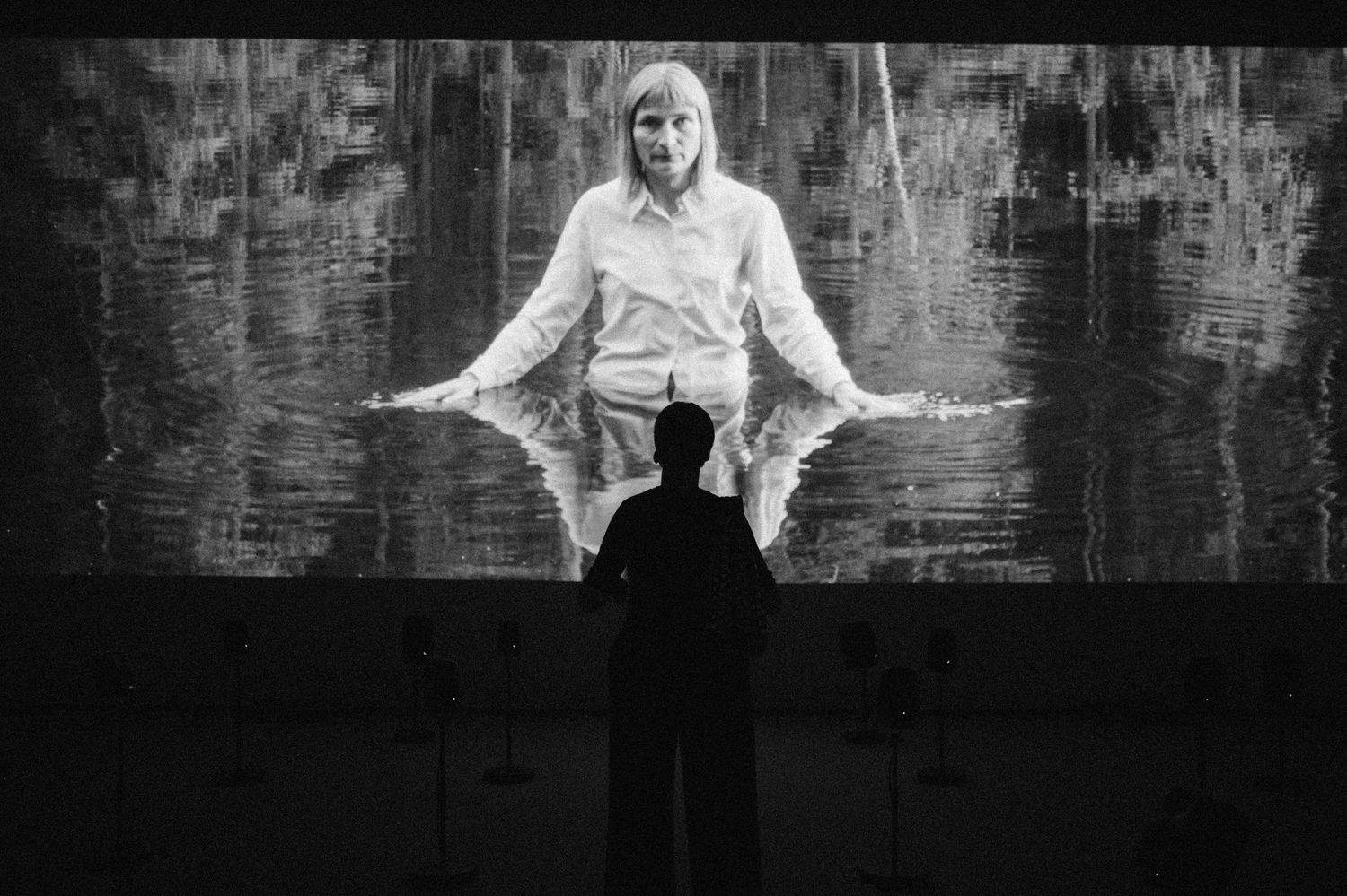 Crno-bijela umjetnička fotografija koja prikazuje osobu u skoku i okretu sa raširenim rukama naspram tamne pozadine u muzeju Kunstsilo.