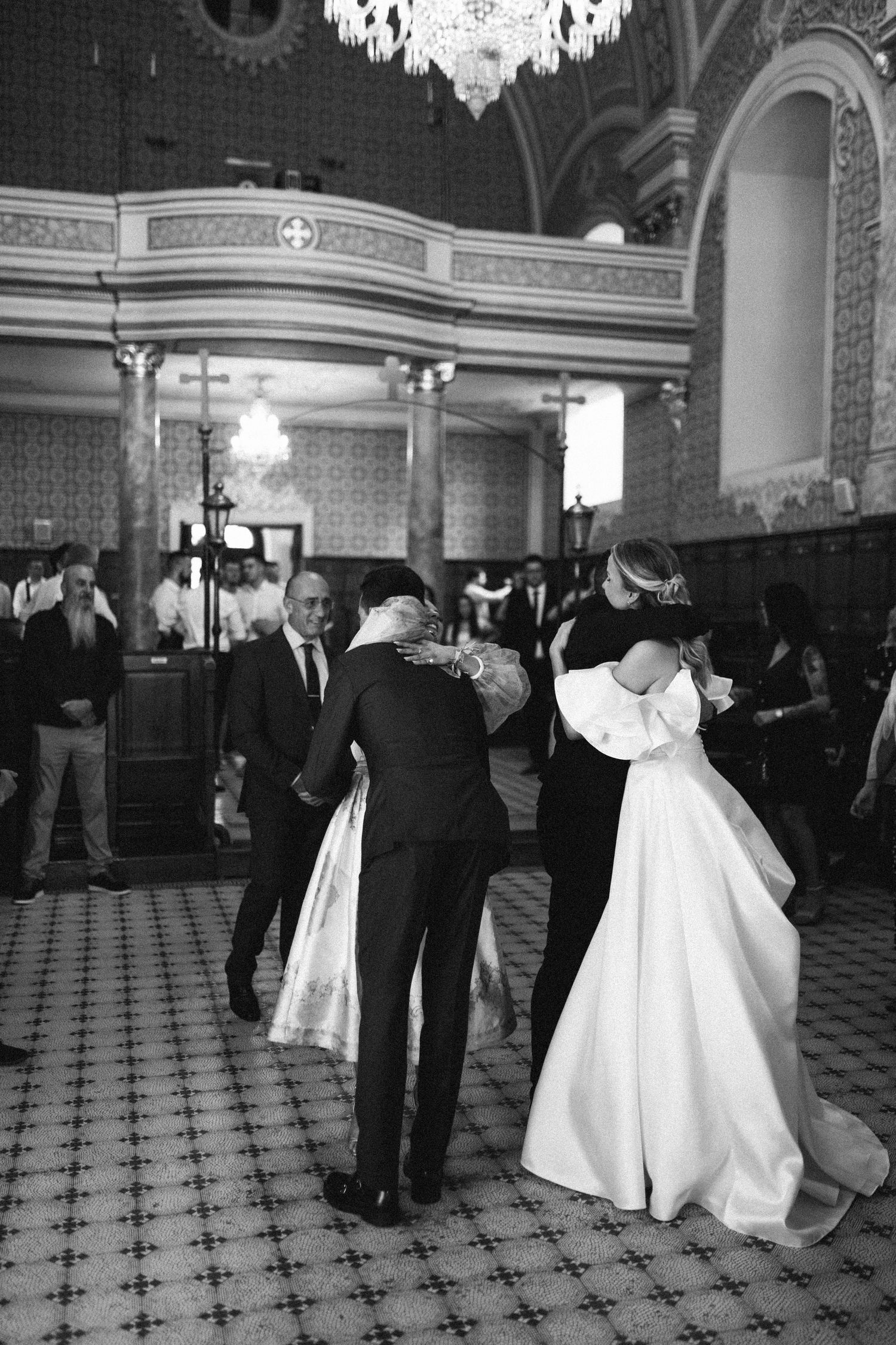 Couples dancing in an elegant ballroom with ornate architecture and a black and white checkered floor pattern.
