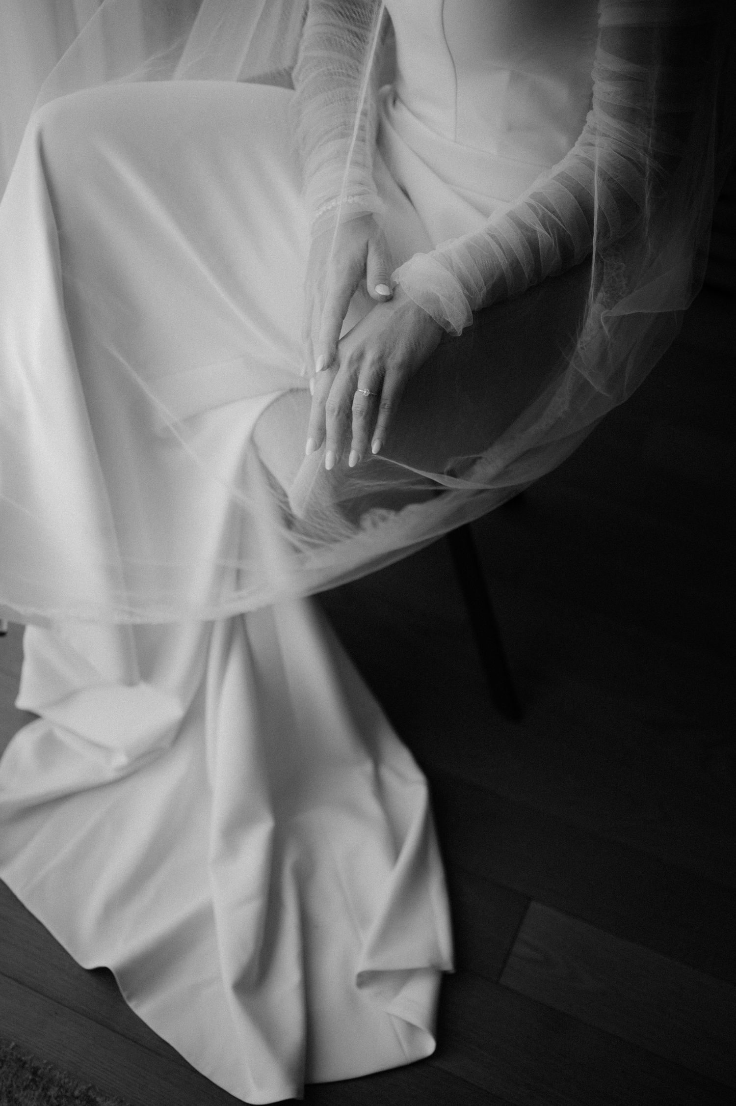 Black and white artistic close-up shots of a flowing white wedding dress showing delicate fabric details and movement.