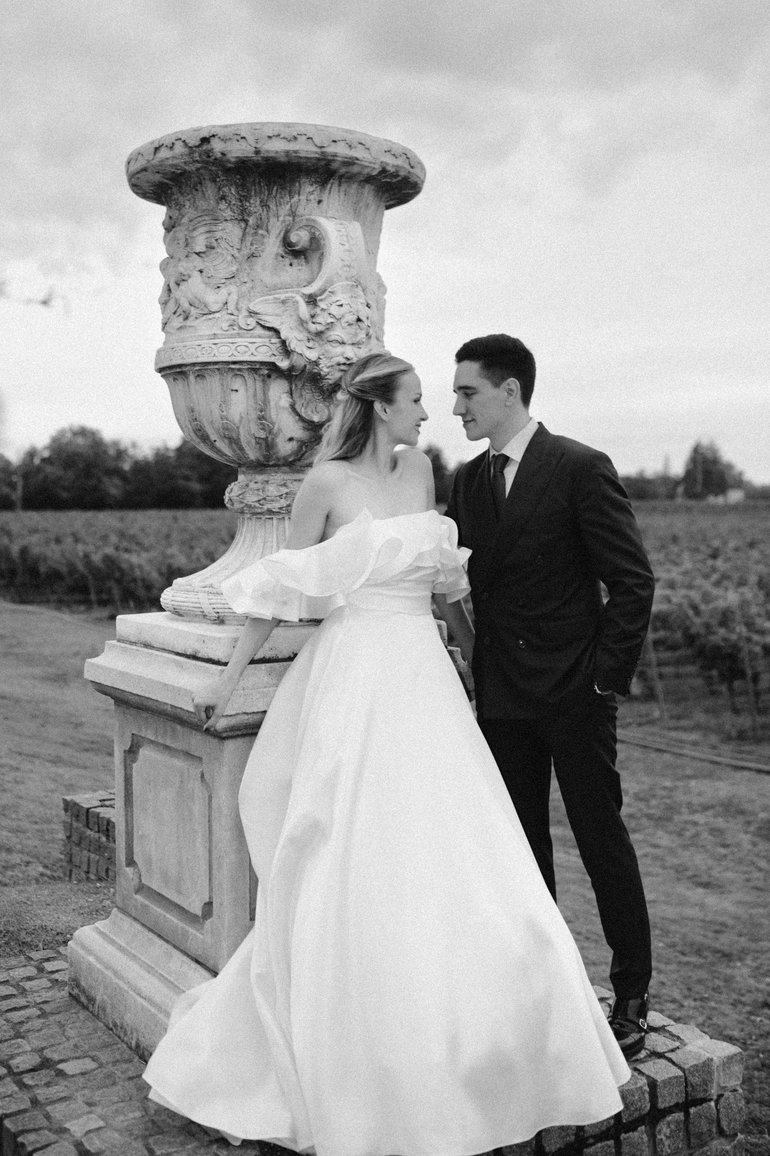 Romantic wedding portraits taken near decorative stone pillars in an outdoor setting.