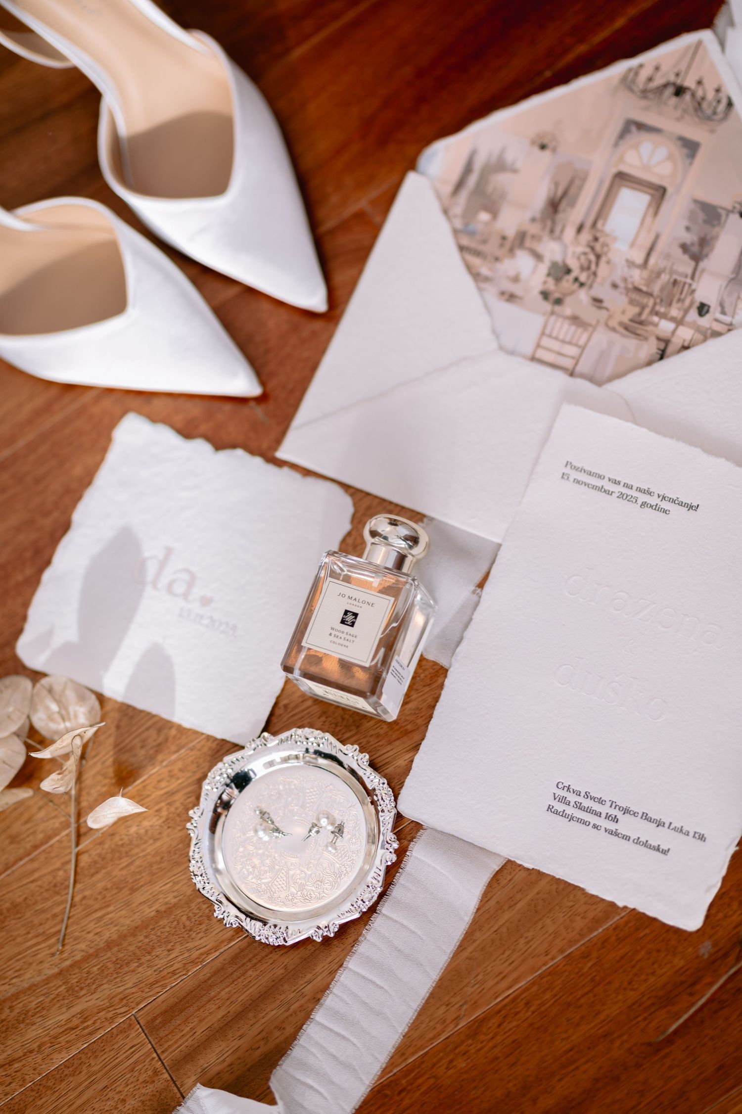 Wedding accessories and stationery flatlay featuring watch and invitations on wooden table.