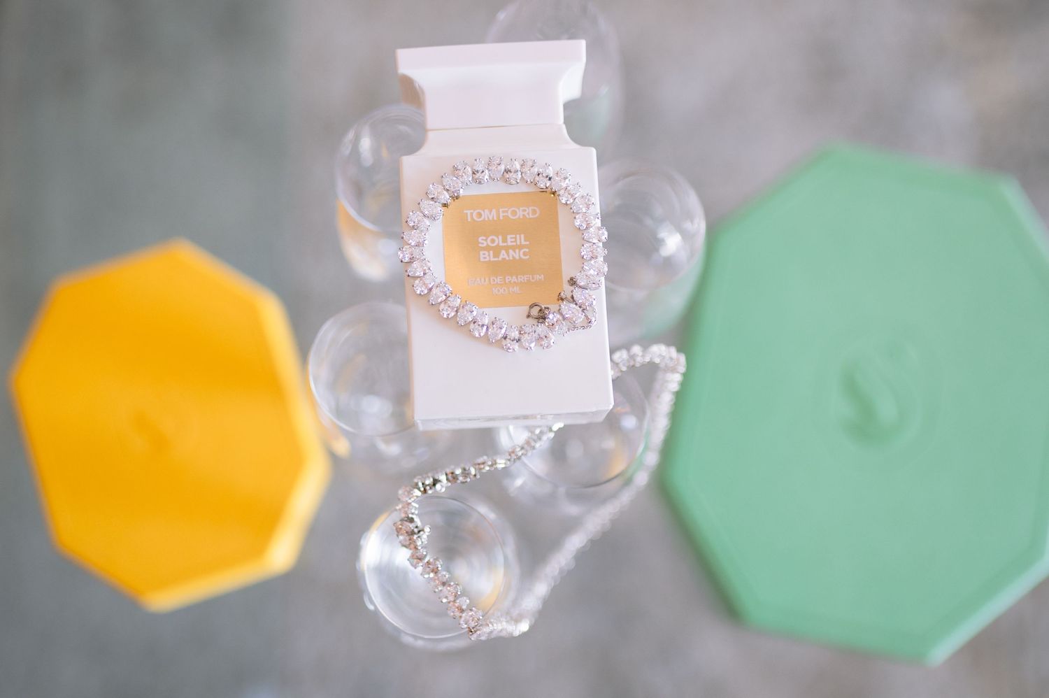 A close-up shot of clear glass perfume bottles with colorful hexagonal lids in mint green and yellow shades.