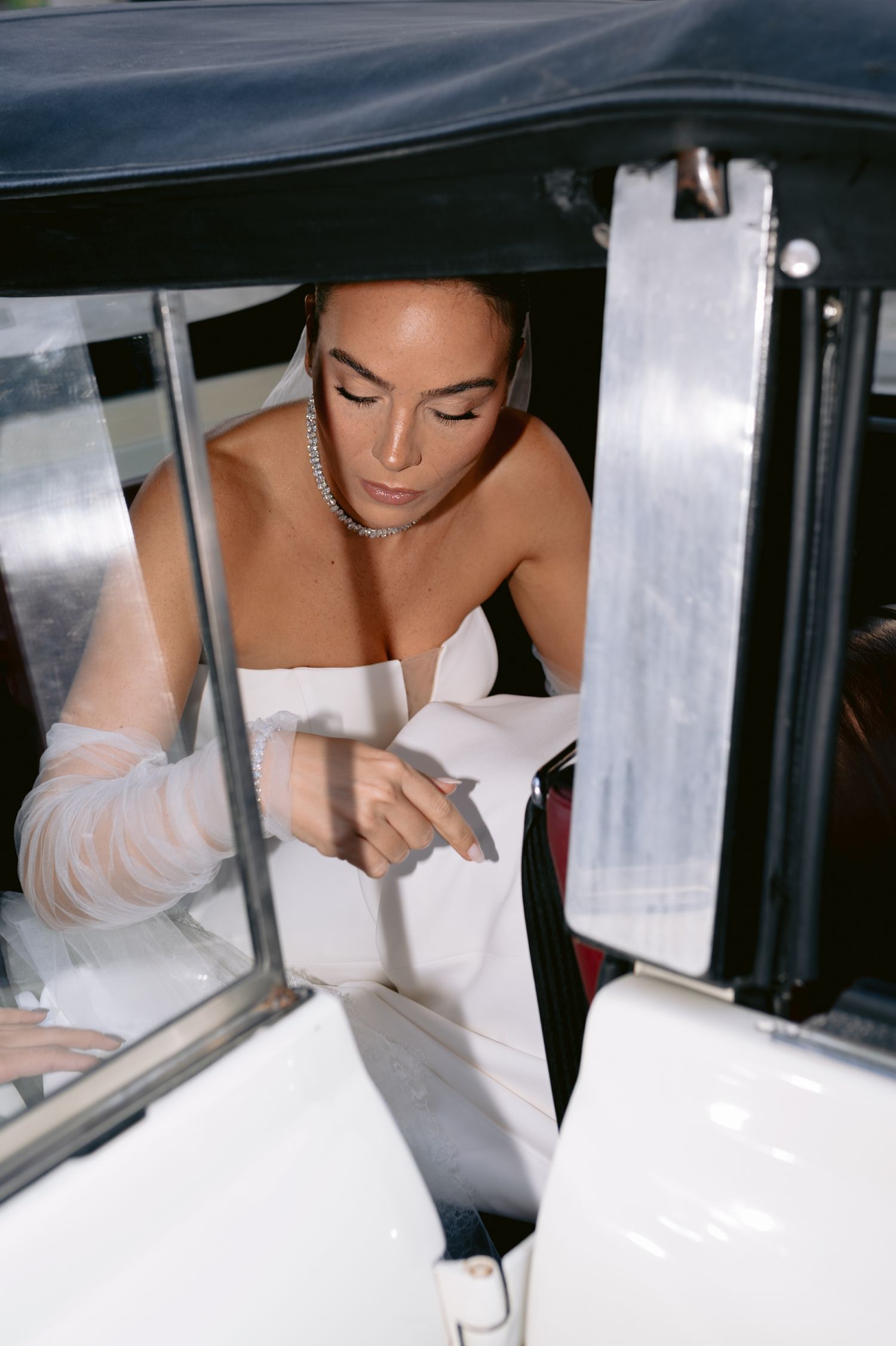 Person in white dress looking down through car window in sequence of similar shots.