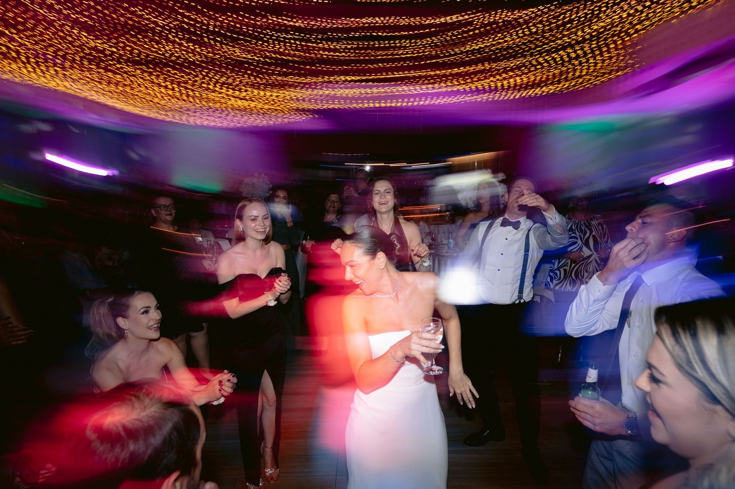 A sequence of blurred motion shots showing people dancing and celebrating at a nightclub with colorful lighting.