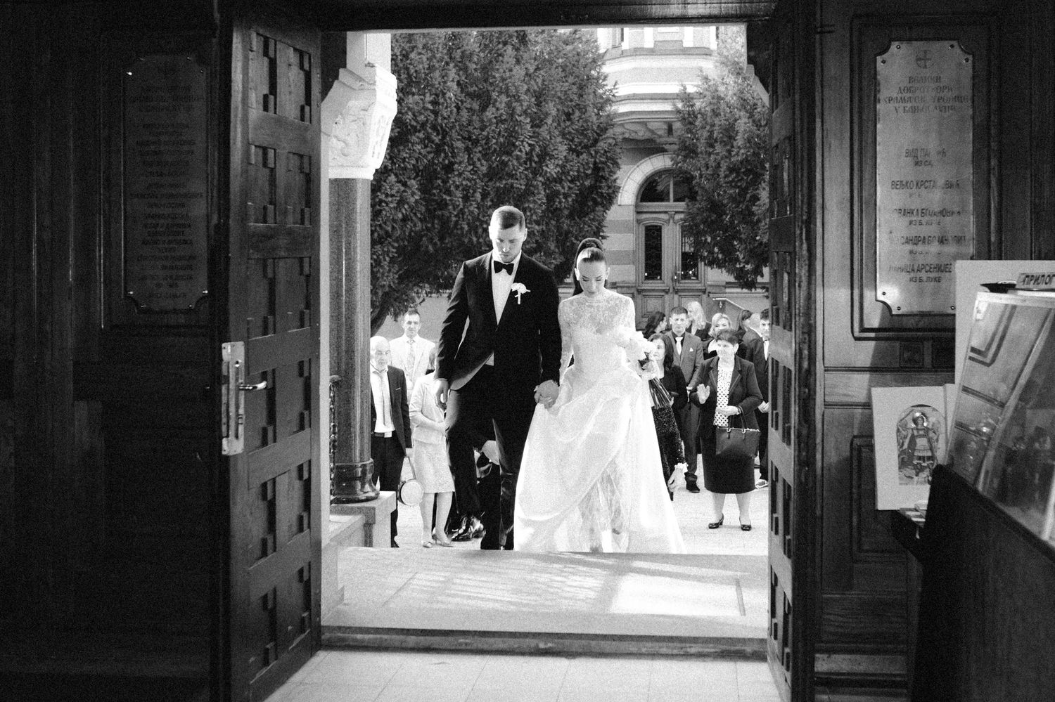 Black and white wedding sequence showing couple walking through ornate building hallway.