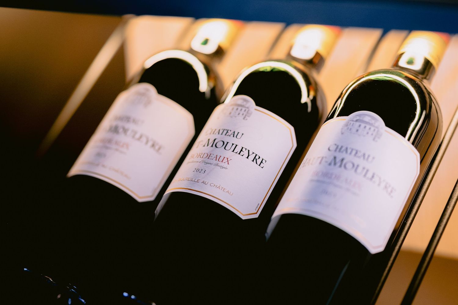 Three wine bottles arranged in wooden display case.
