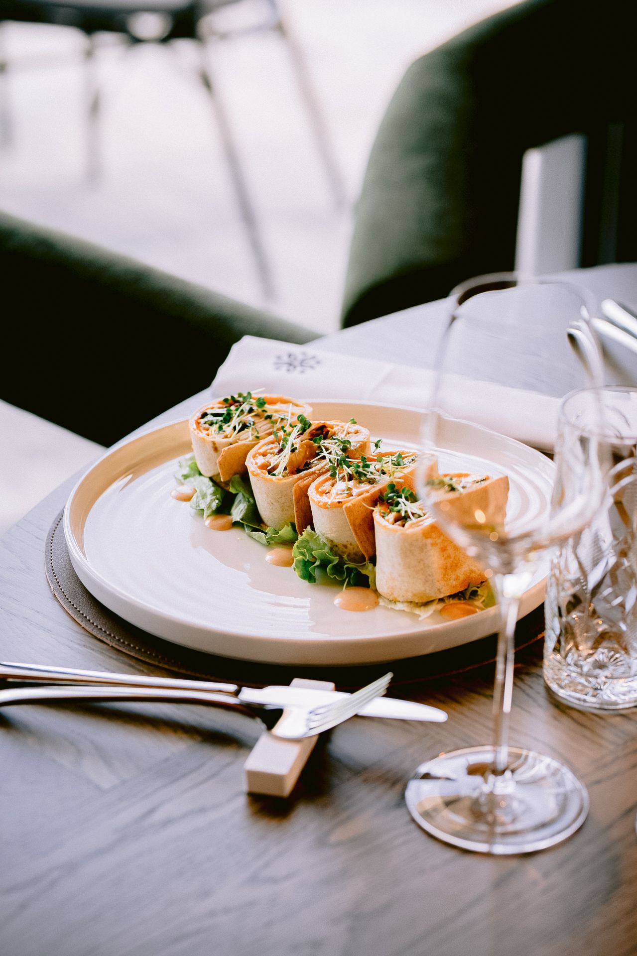 Elegant plated dish with garnishes served on white tablecloth with wine glasses.