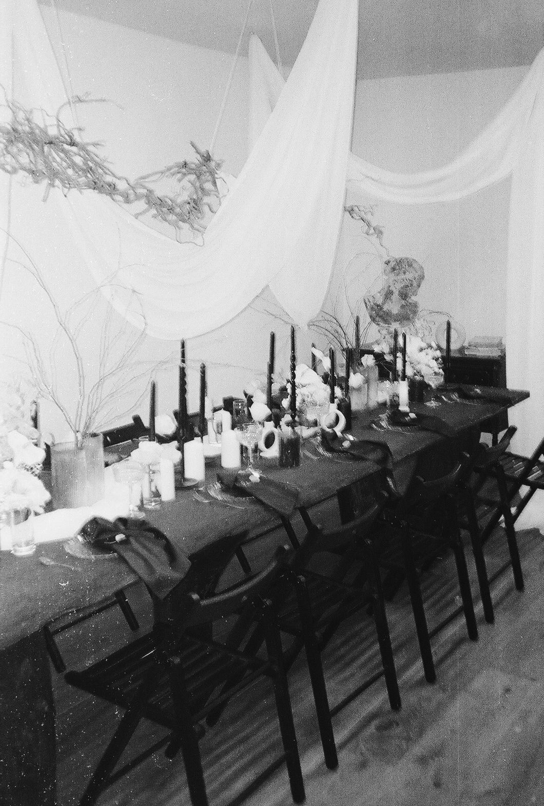 Black and white photo showing a row of empty computer workstations with monitors and chairs in a dimly lit room.