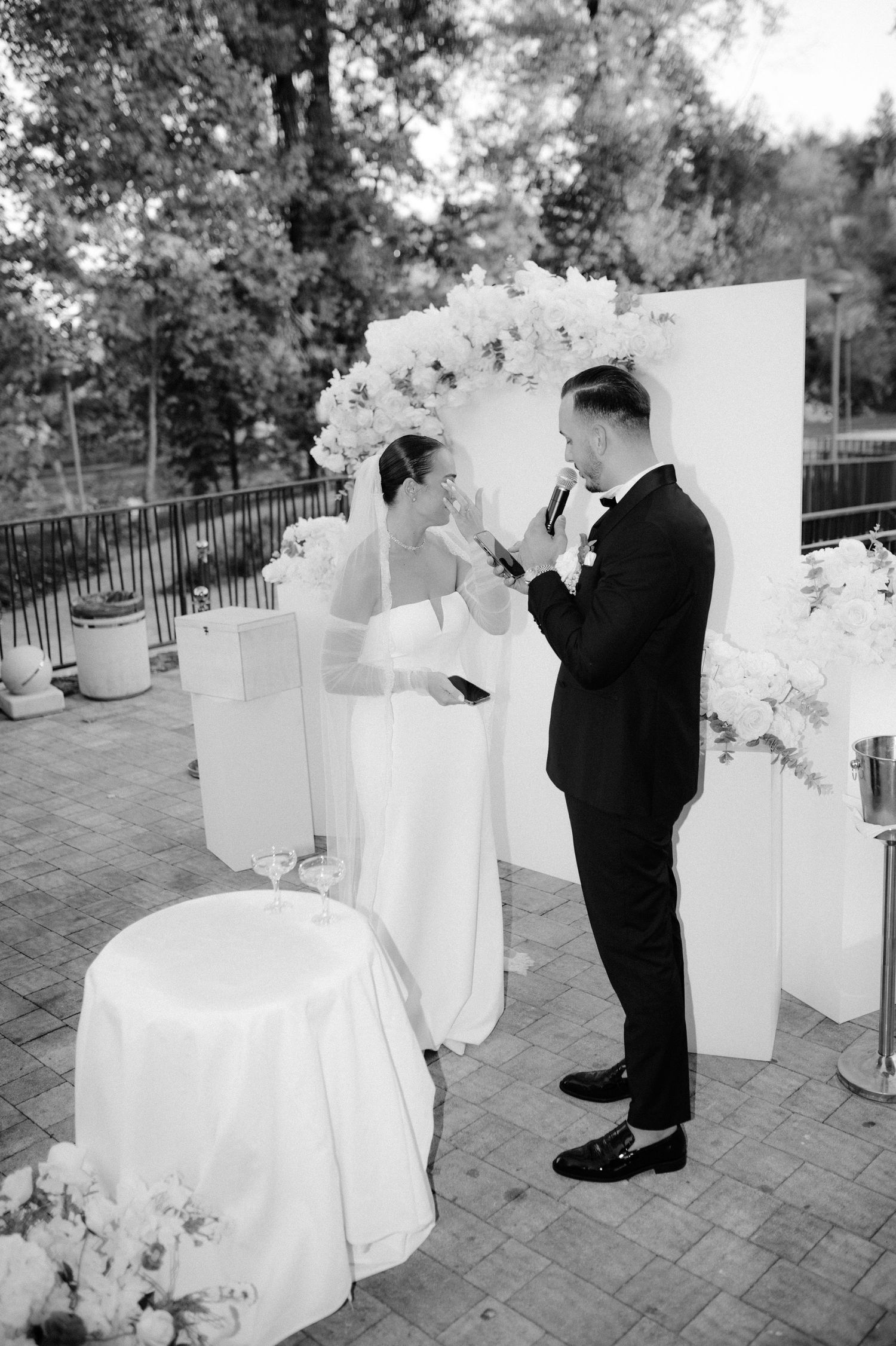 A black and white wedding photo sequence showing a couple sharing a romantic moment among decorative white panels outdoors.