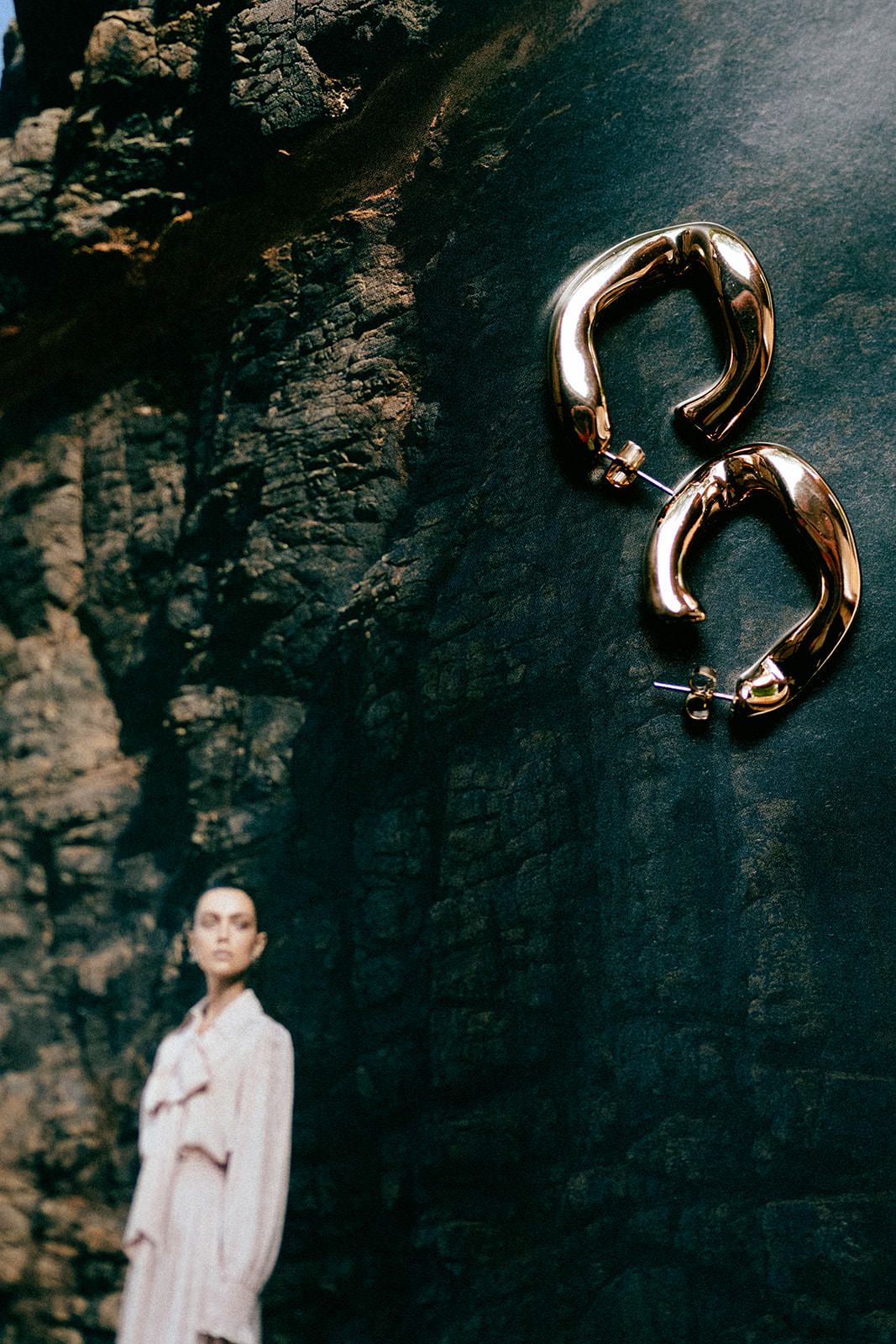 Artistic composition of gold jewelry against dark textured background.