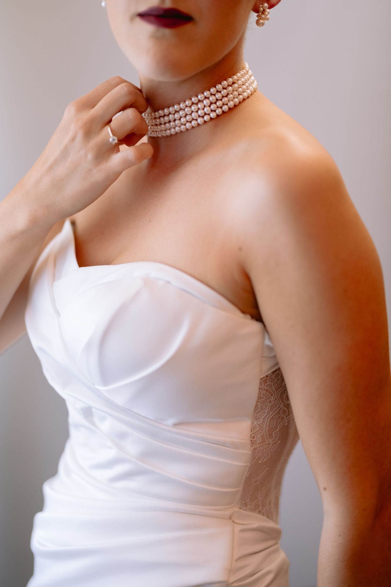 Close-up of pearl choker necklace with white strapless wedding dress bodice.