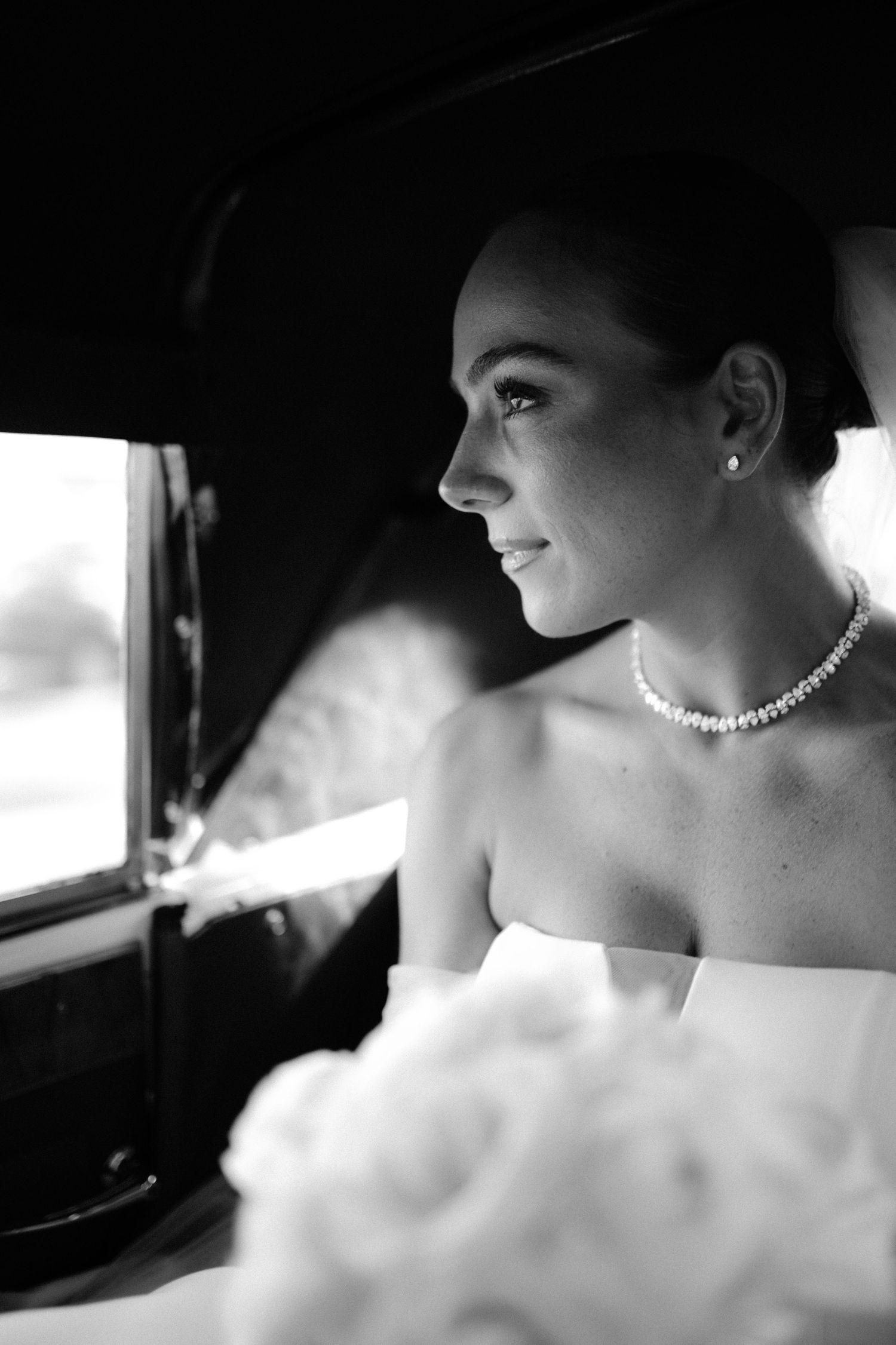 Artistic black and white bridal portrait highlighting elegant jewelry and profile.
