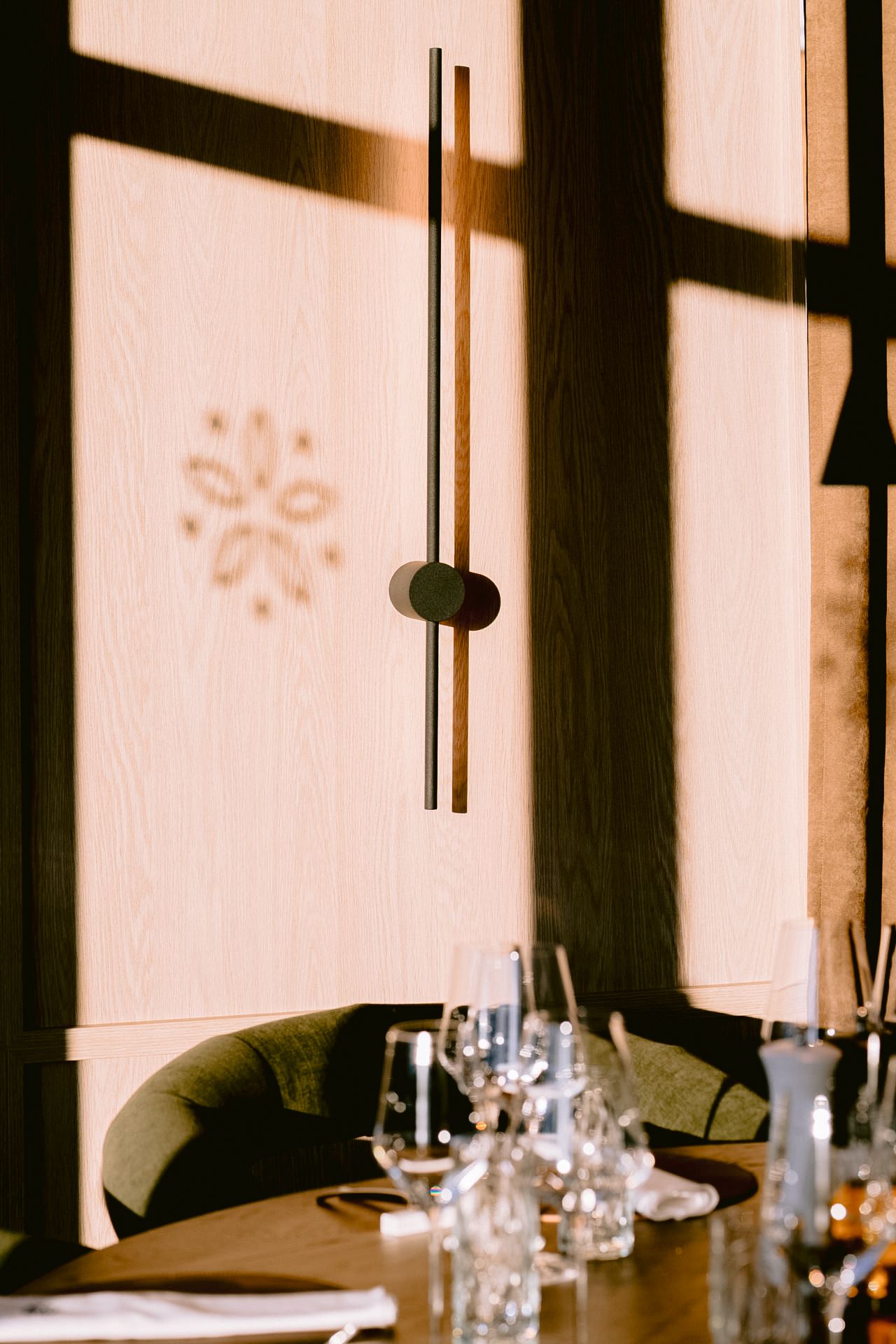 Elegant restaurant interior with wood-paneled walls, modern wall sconce, and a table set with crystal glassware.