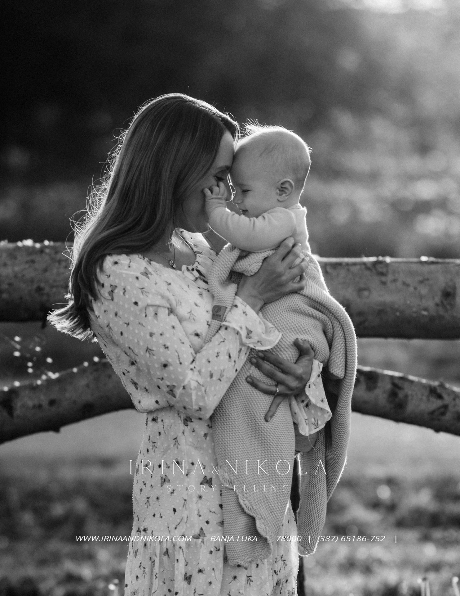 Black and white photo of a mother tenderly holding her baby outdoors, captured by Irina Nikola photography.
