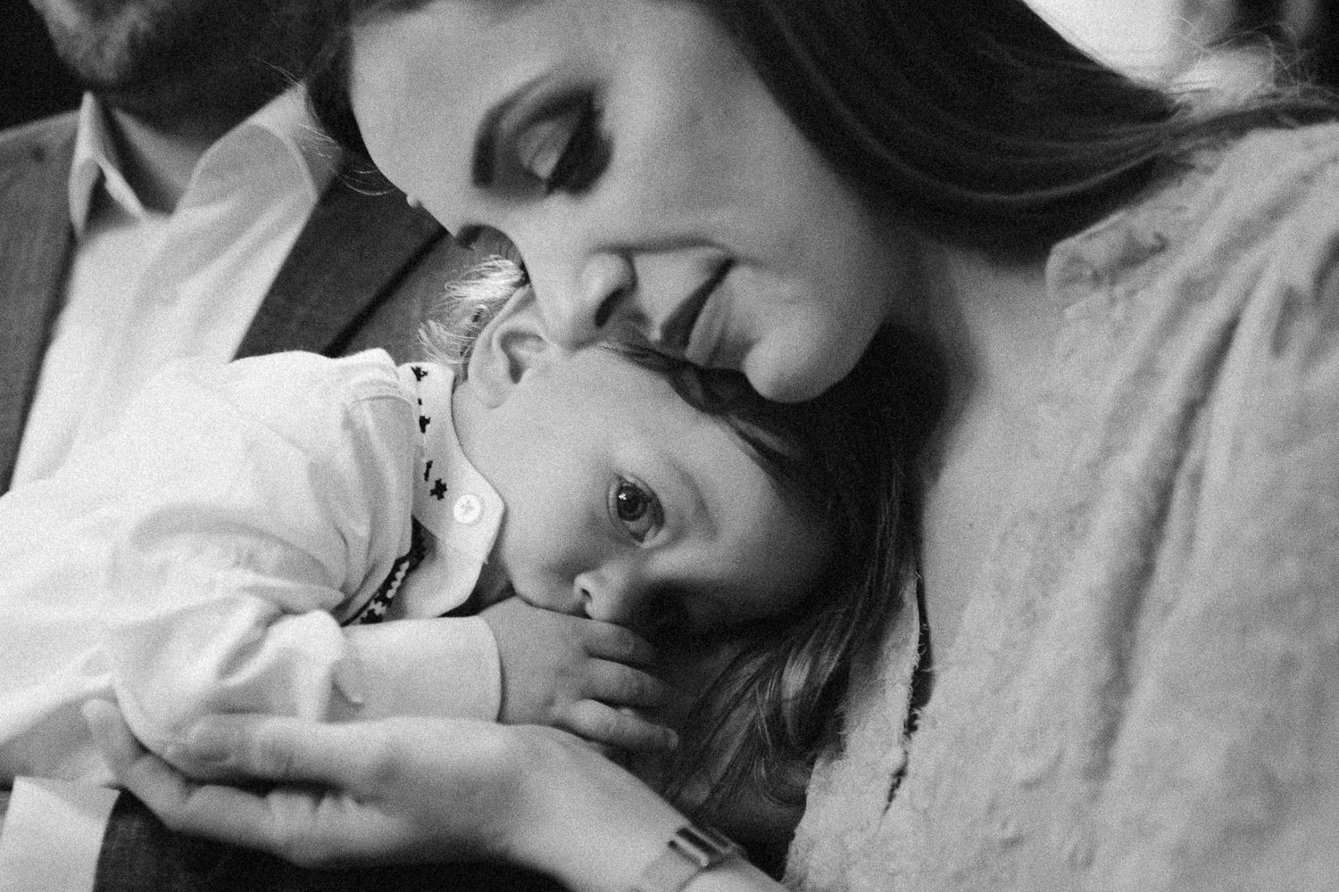 Black and white photo of a mother tenderly kissing her young child, capturing a heartfelt moment of love.