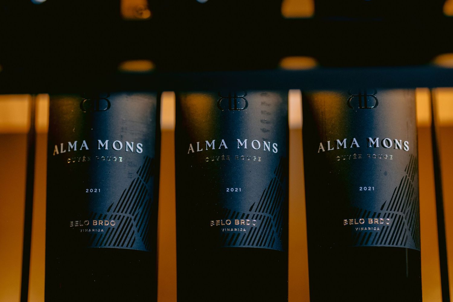 Three bottles of Alma Mons wine displayed with blue labels.