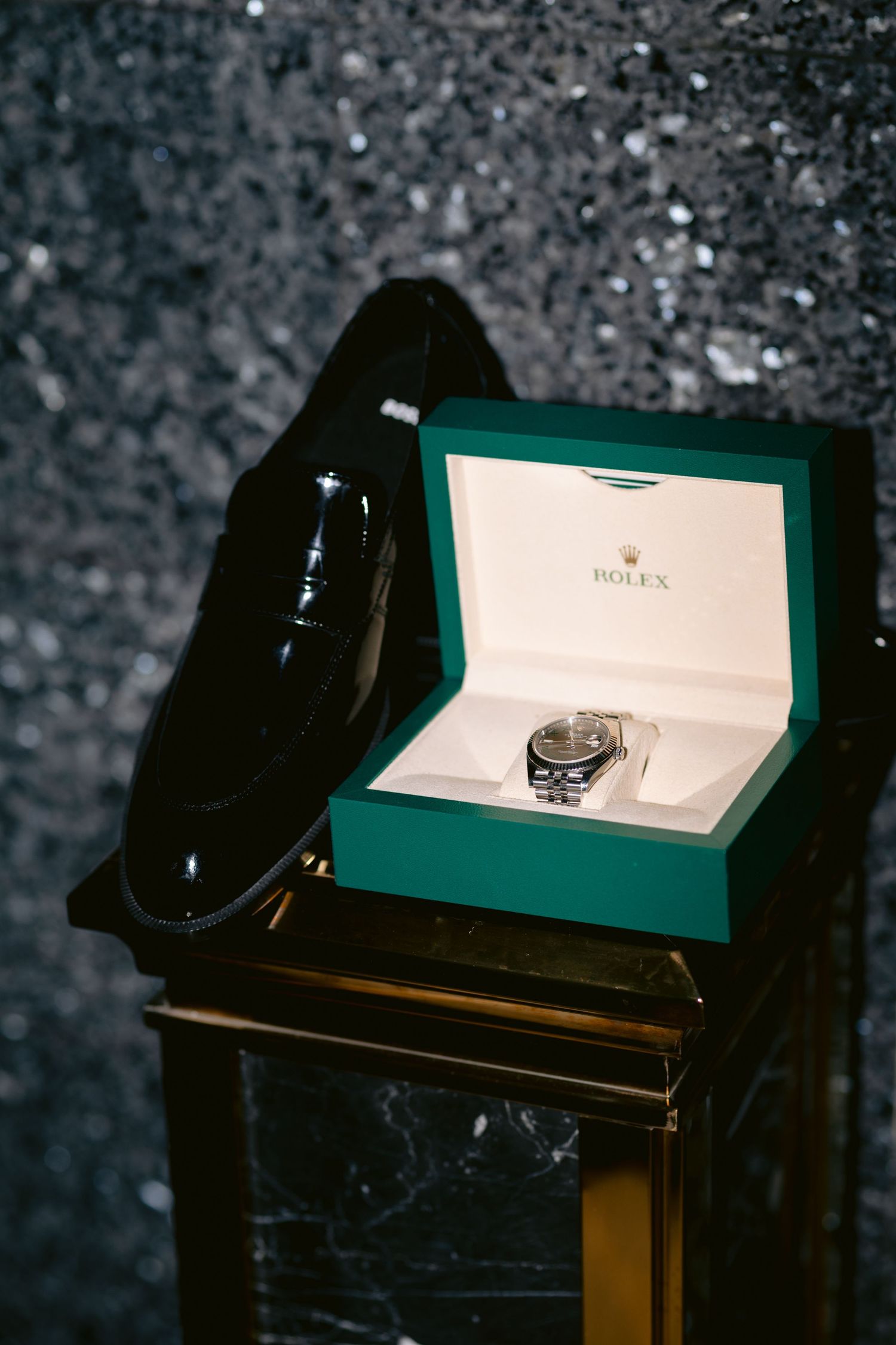 A vintage black rotary telephone sits beside an illuminated display box on a dark wooden table in moody lighting.
