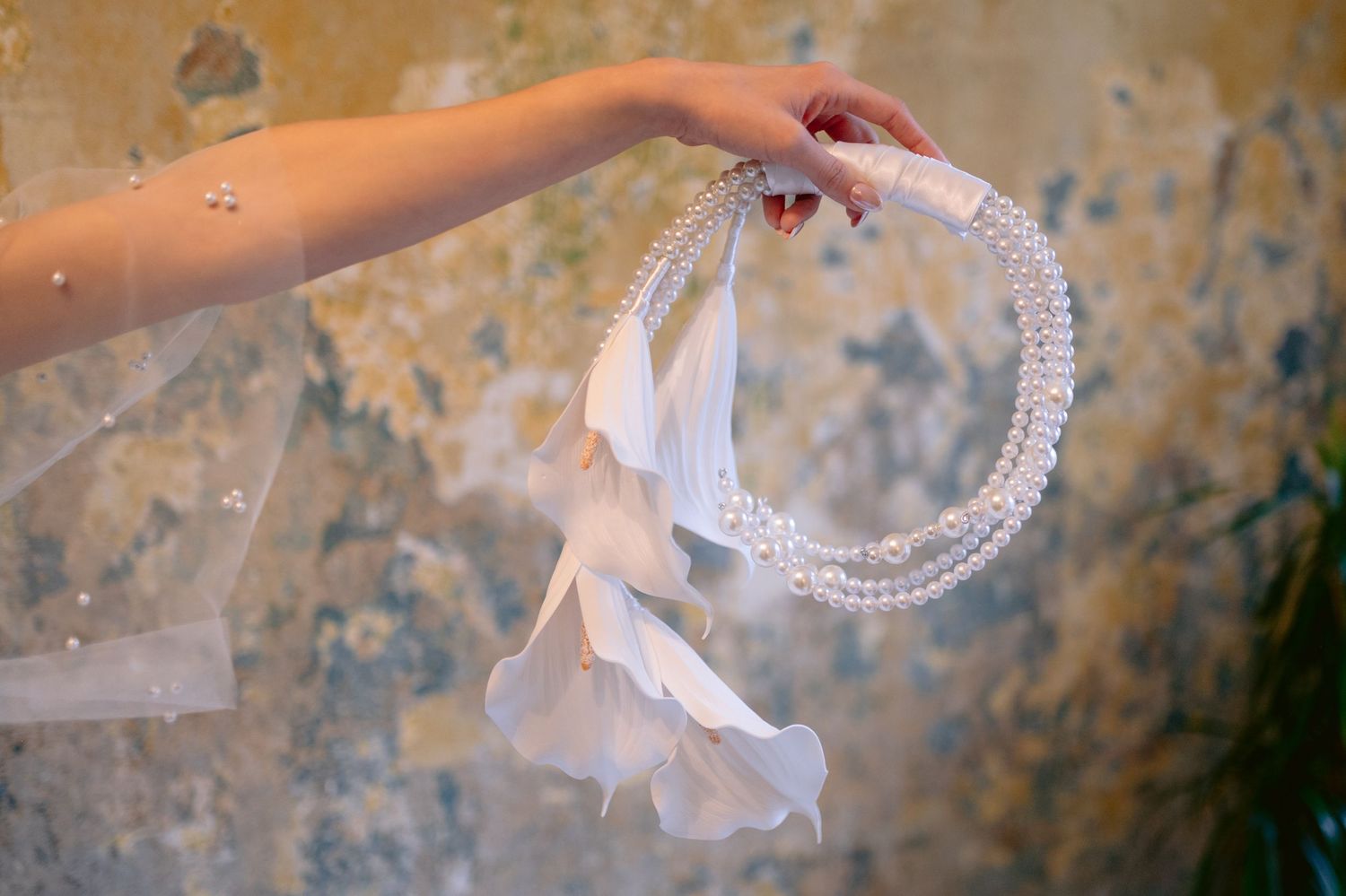 Delicate pearl accessories and ribbons captured against textured golden background.