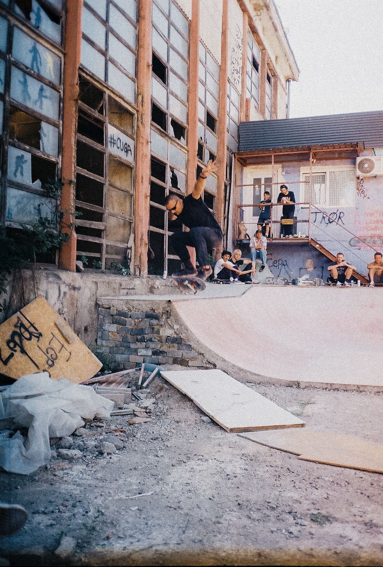 Sequence of action shots showing skateboarding tricks being performed on concrete ramps in an abandoned urban space.