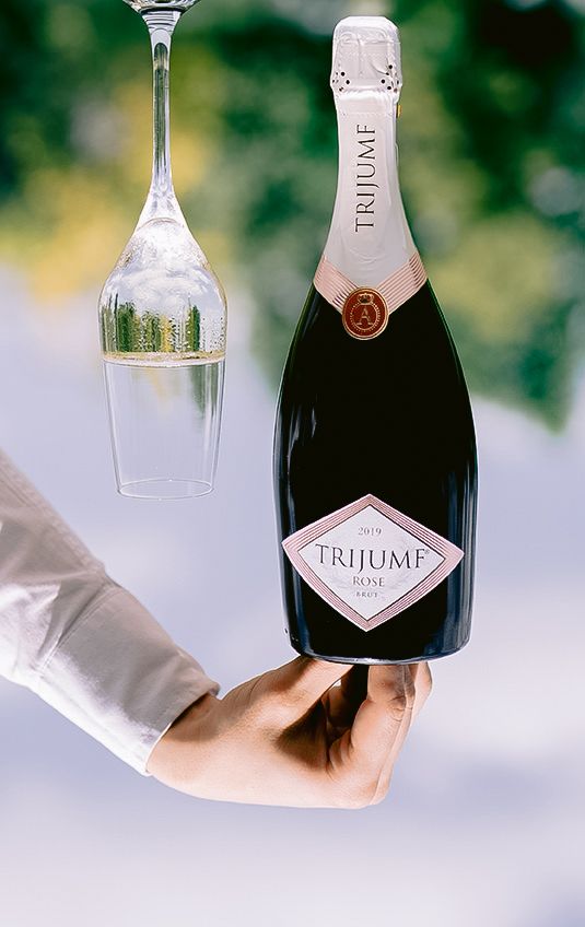 Multiple bottles of Trijumf wine displayed in an artistic arrangement against a light background.