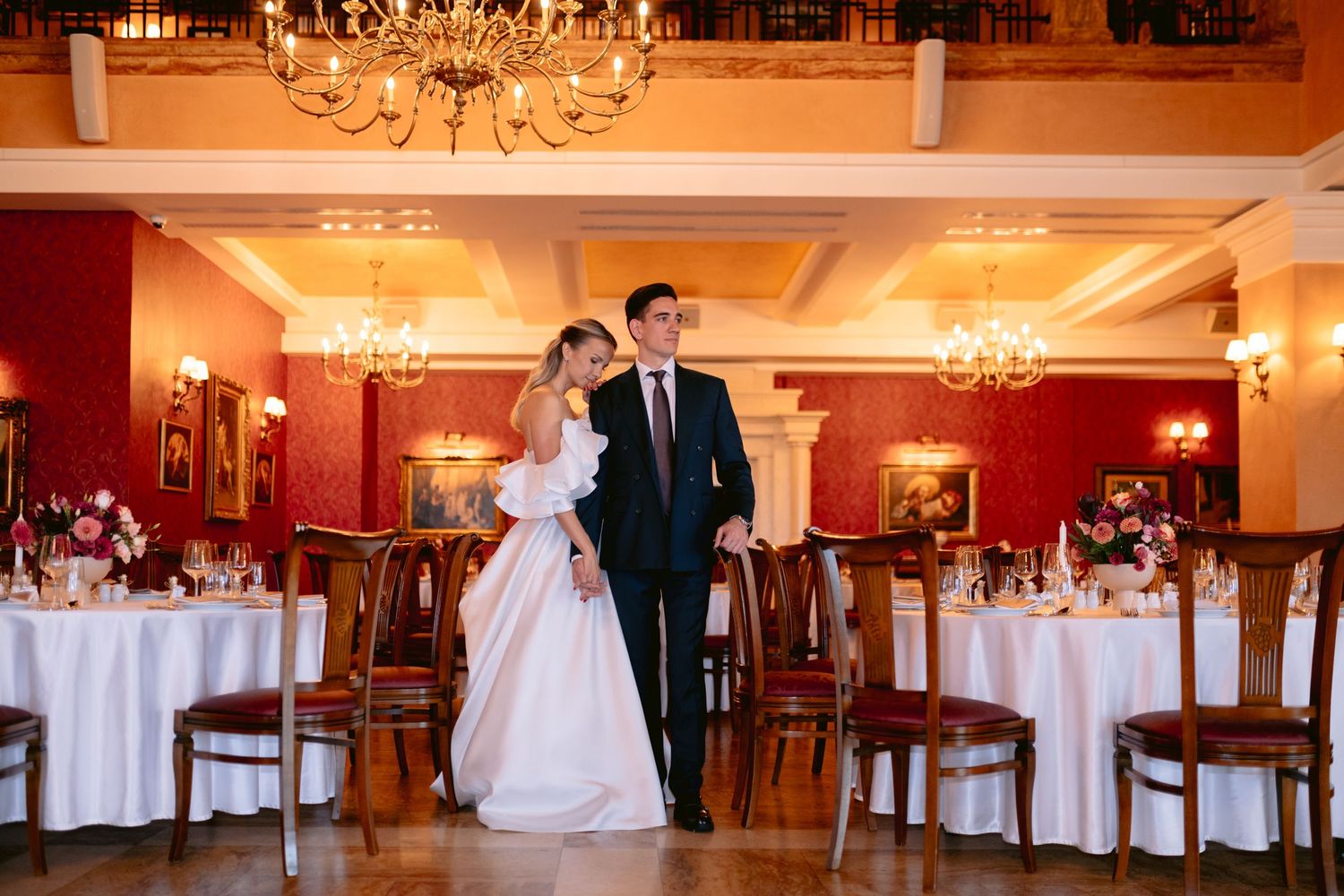 Elegant wedding reception hall with crystal chandeliers and tables set with white linens.