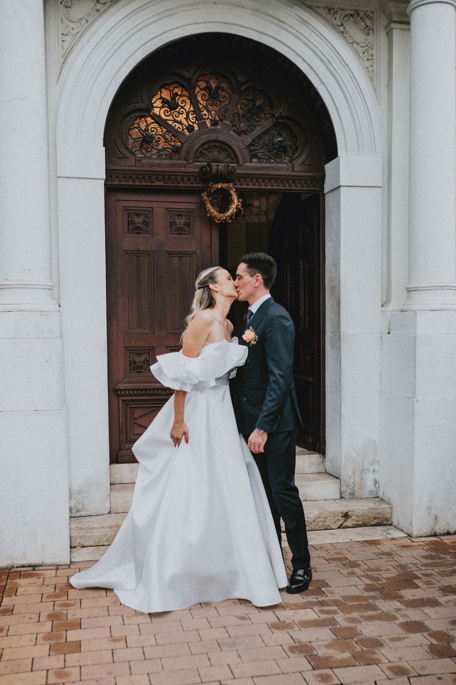 A romantic wedding couple shares three intimate moments in front of an ornate white church entrance with columns.