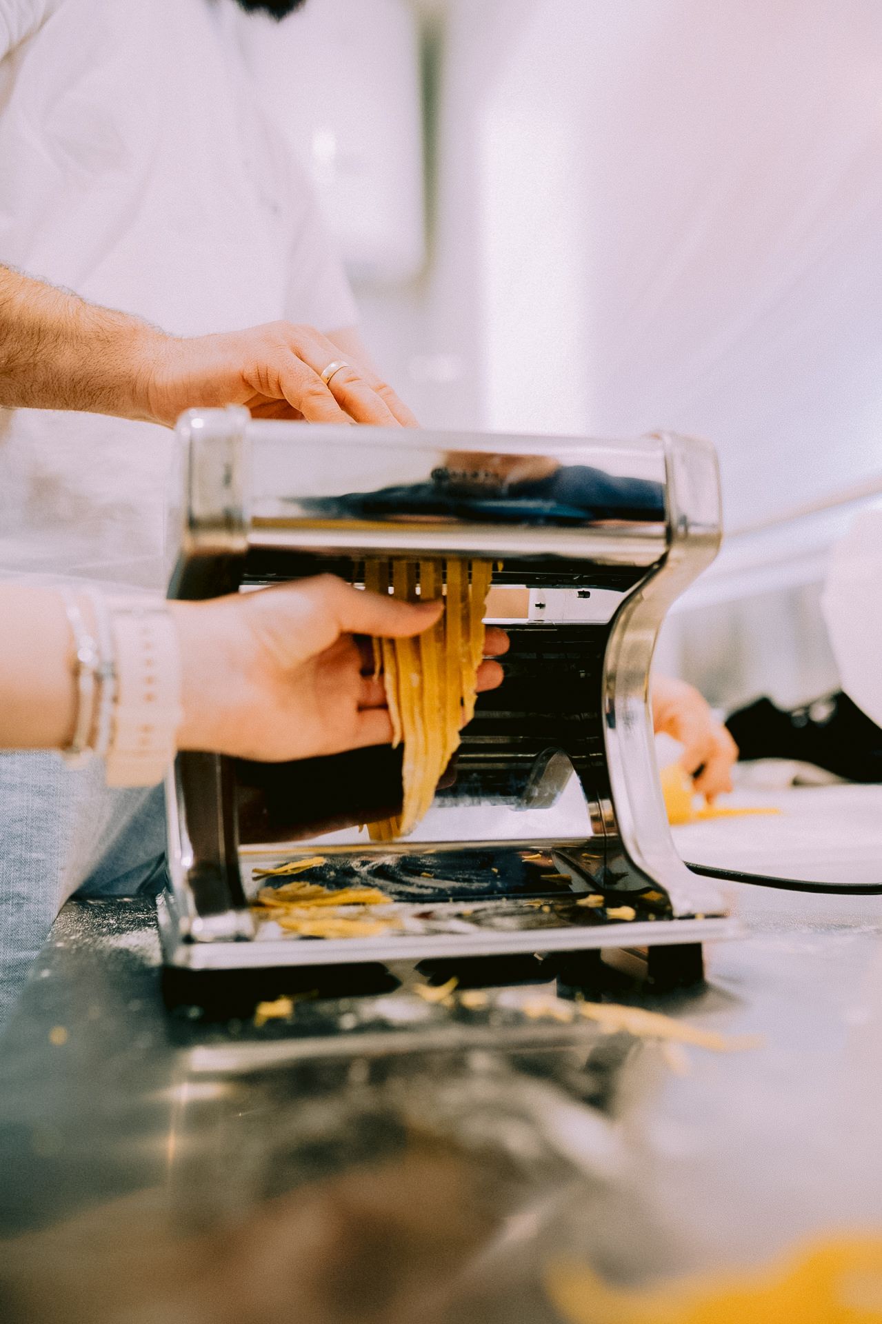 Fresh pasta being made by hand on a dark surface.