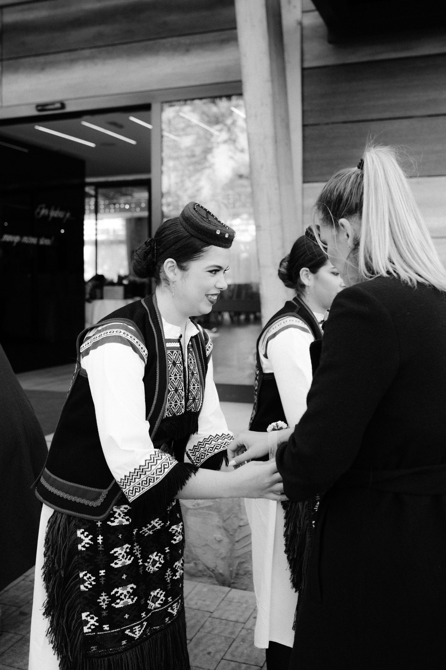 A series of black and white photos showing people in traditional Nordic sweater vests interacting in a public space.