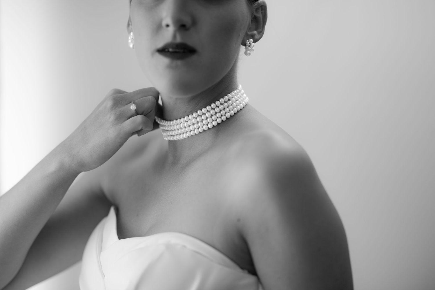 Elegant bridal portrait featuring a pearl choker necklace and strapless dress.
