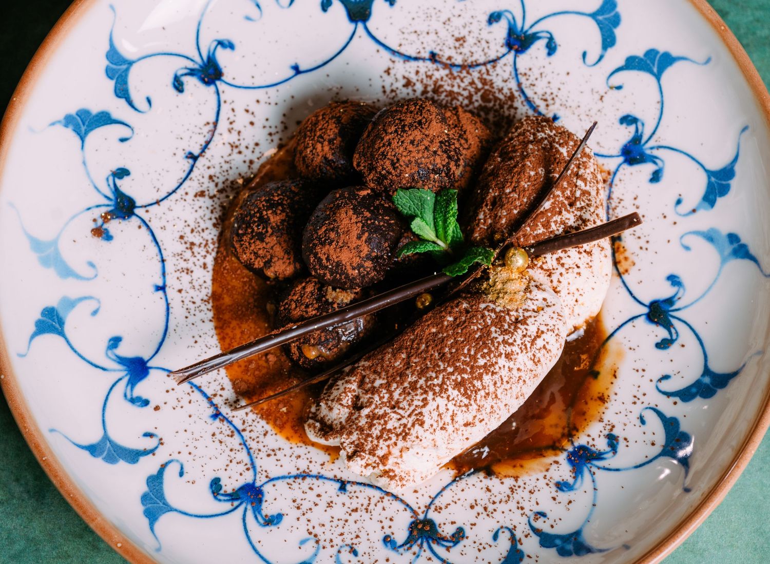 Decorative blue and white plates with dark meat dish garnished with herbs and dusted with spices.