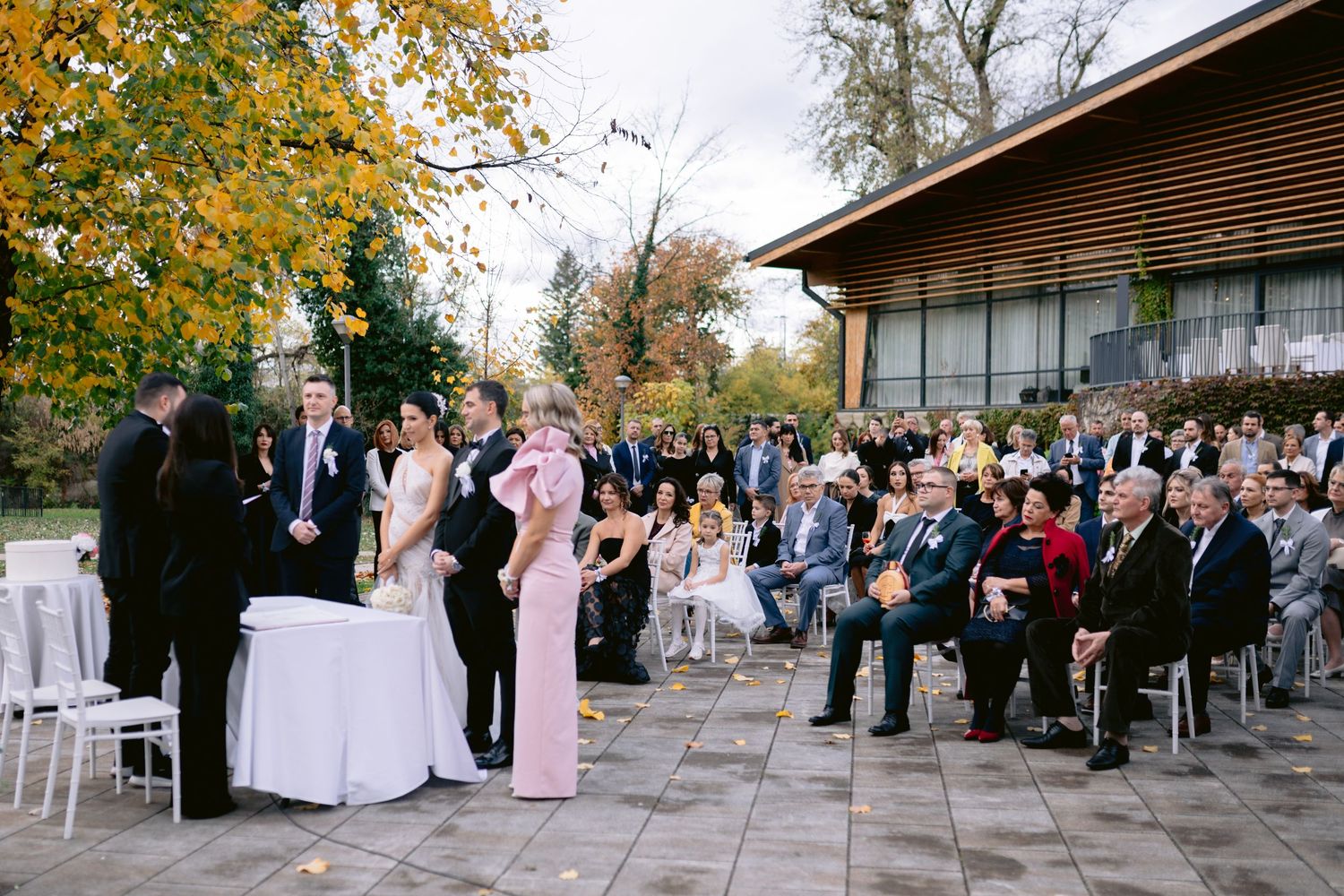 Outdoor wedding ceremony setup with white chairs and autumn trees in background.