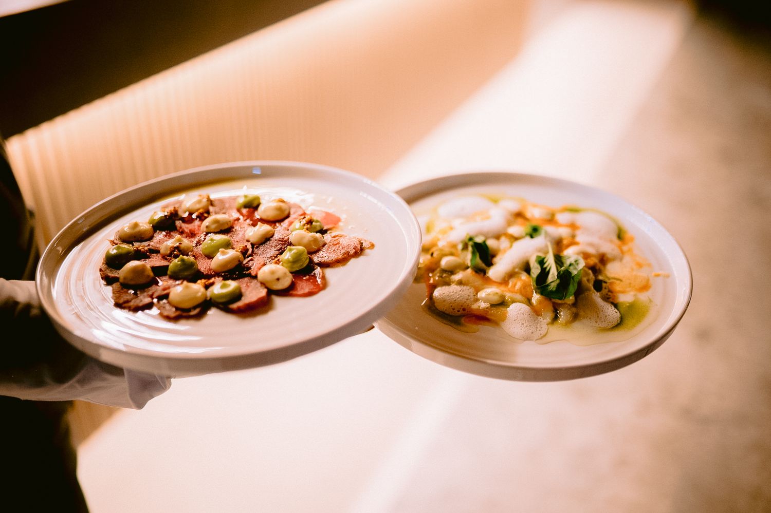 Multiple elegant plated dishes arranged on white serving plates.