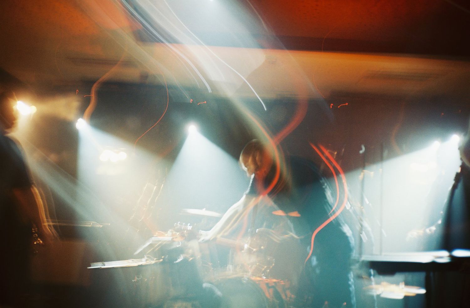 Blurry abstract light trails create a dynamic pattern against a dark background in a long exposure photograph.