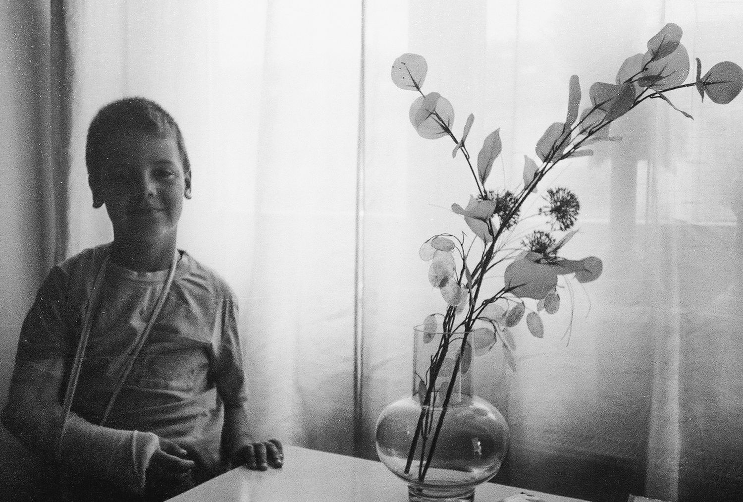 A series of black and white photos showing someone sitting by a window with an orchid plant.