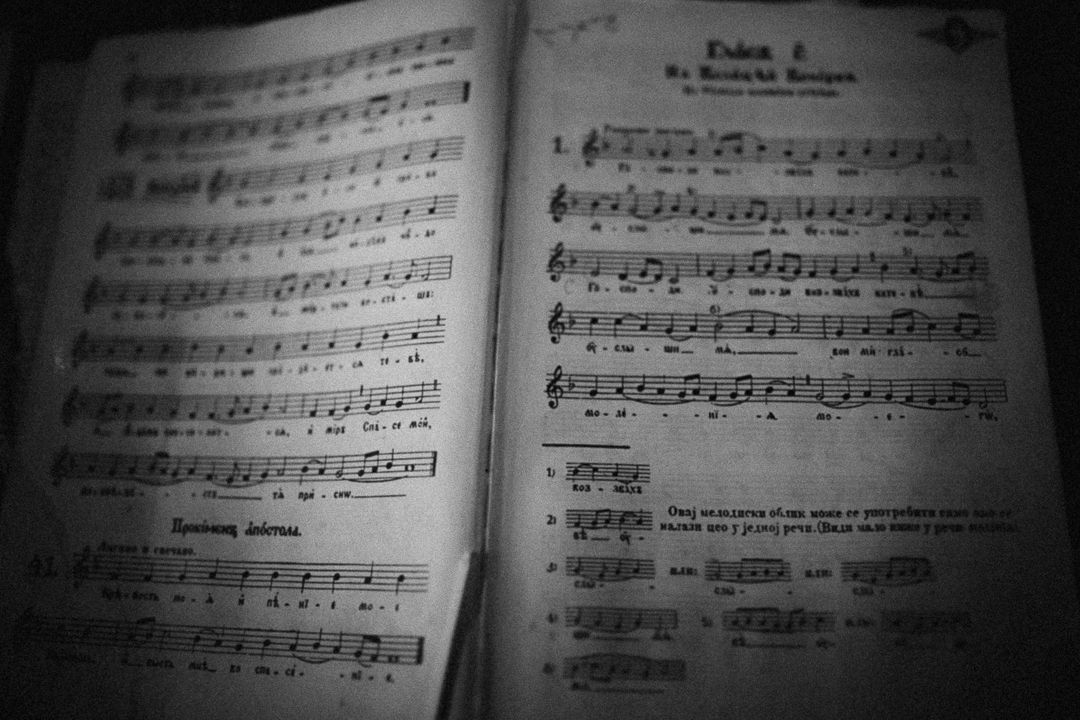 Vintage open sheet music book with musical notes and lyrics in black and white, classic hymnal songbook photography.