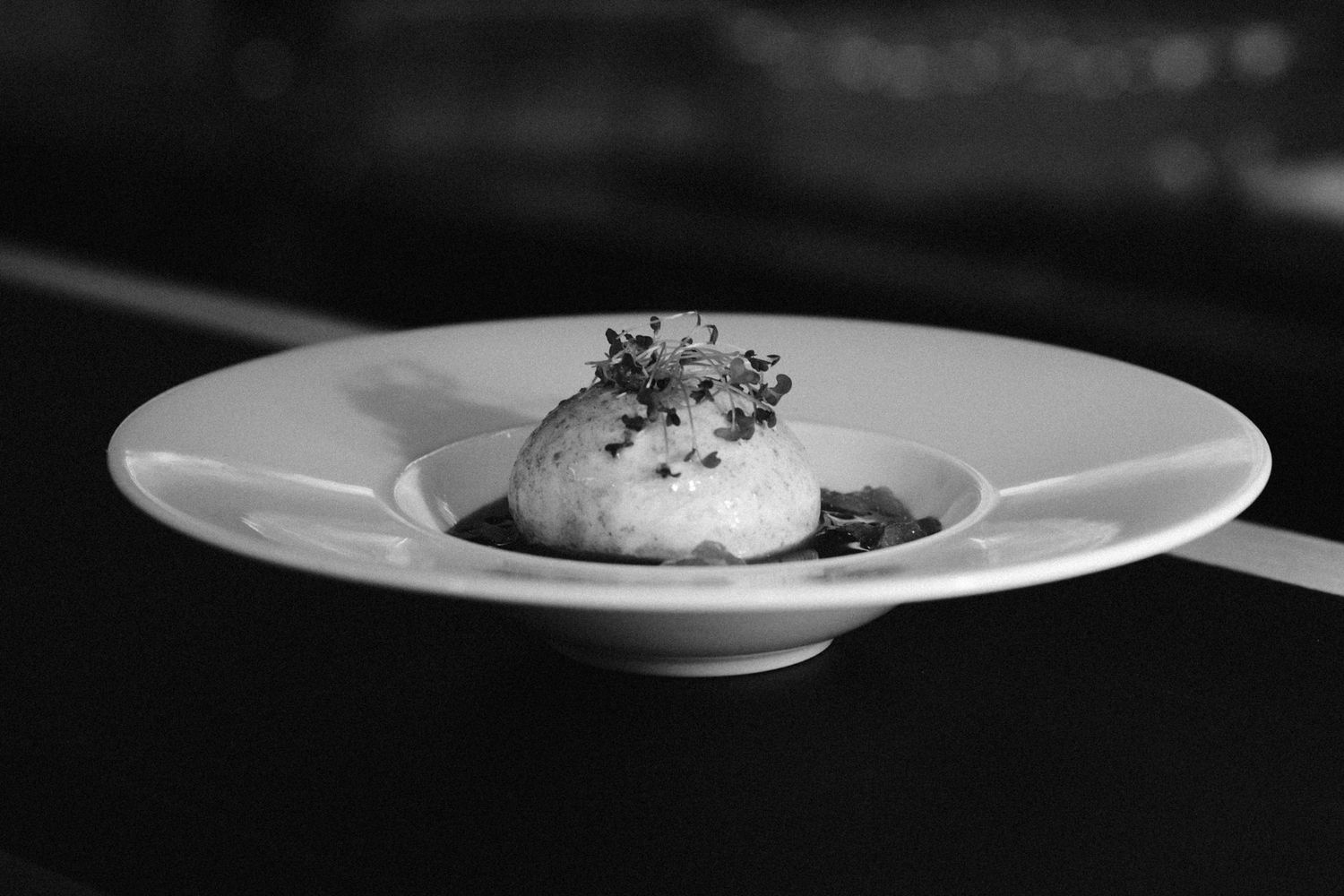 Minimalist black and white photo of plated dishes in fine dining setting.