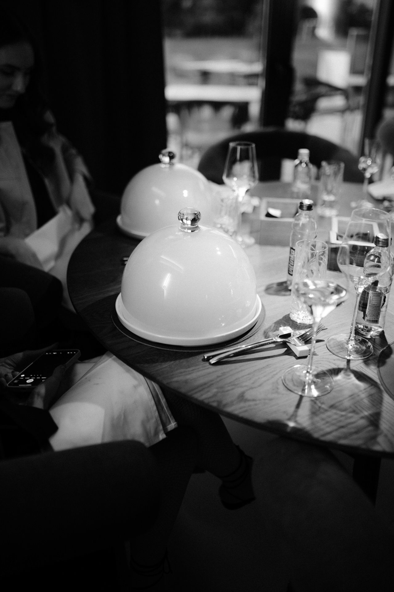 White cloche domes line an elegant dining table setting.