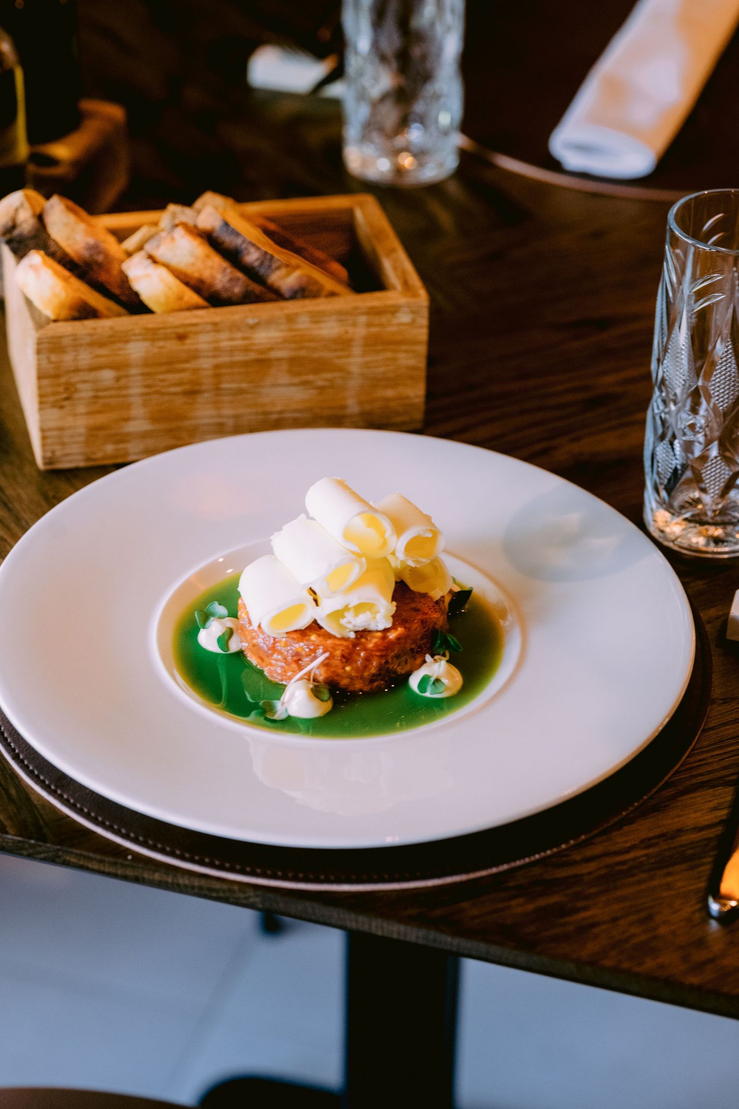 Gourmet dish served with green sauce on white plates in an upscale restaurant setting.