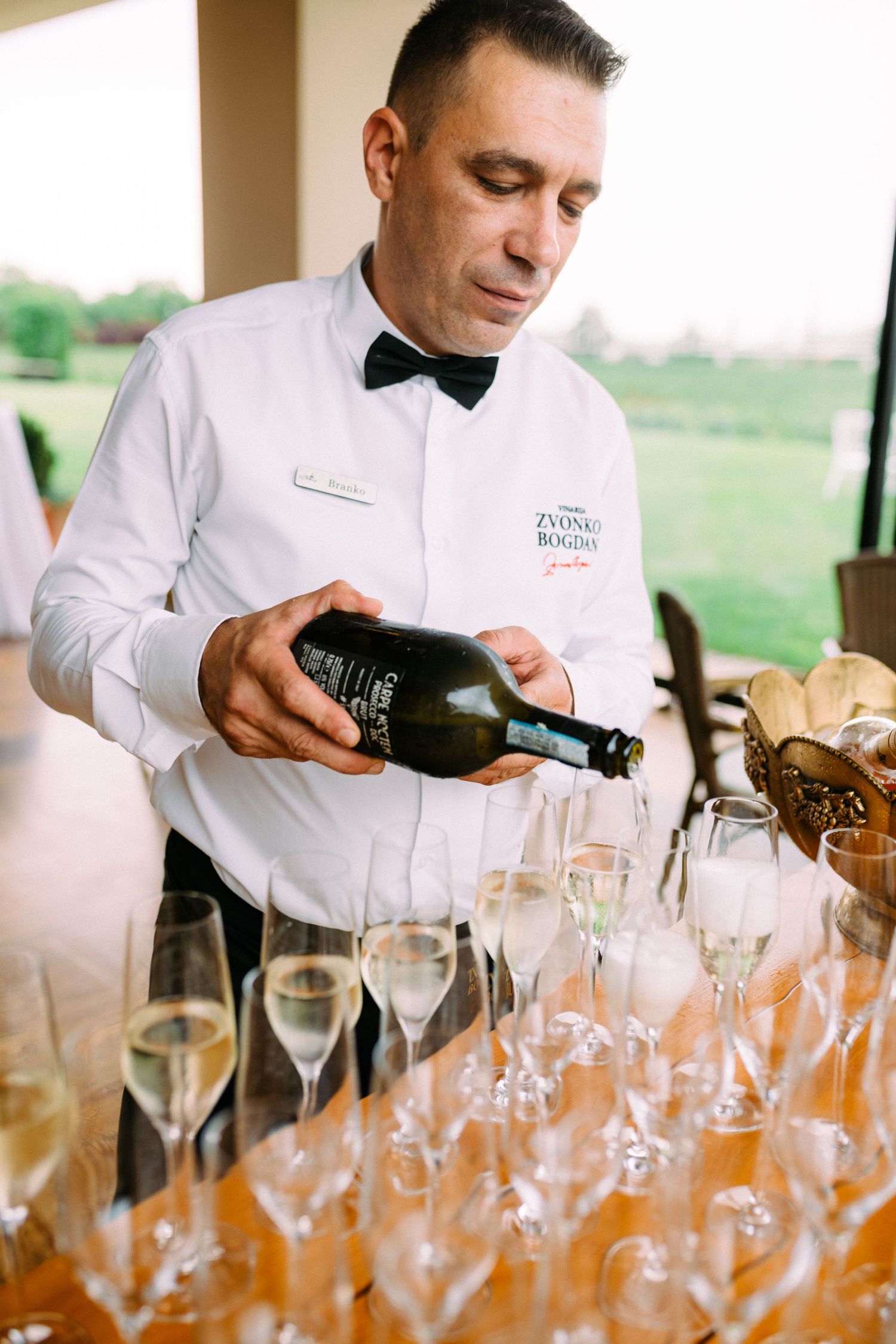 Professional sommelier pours wine into elegant glasses at an upscale event service.