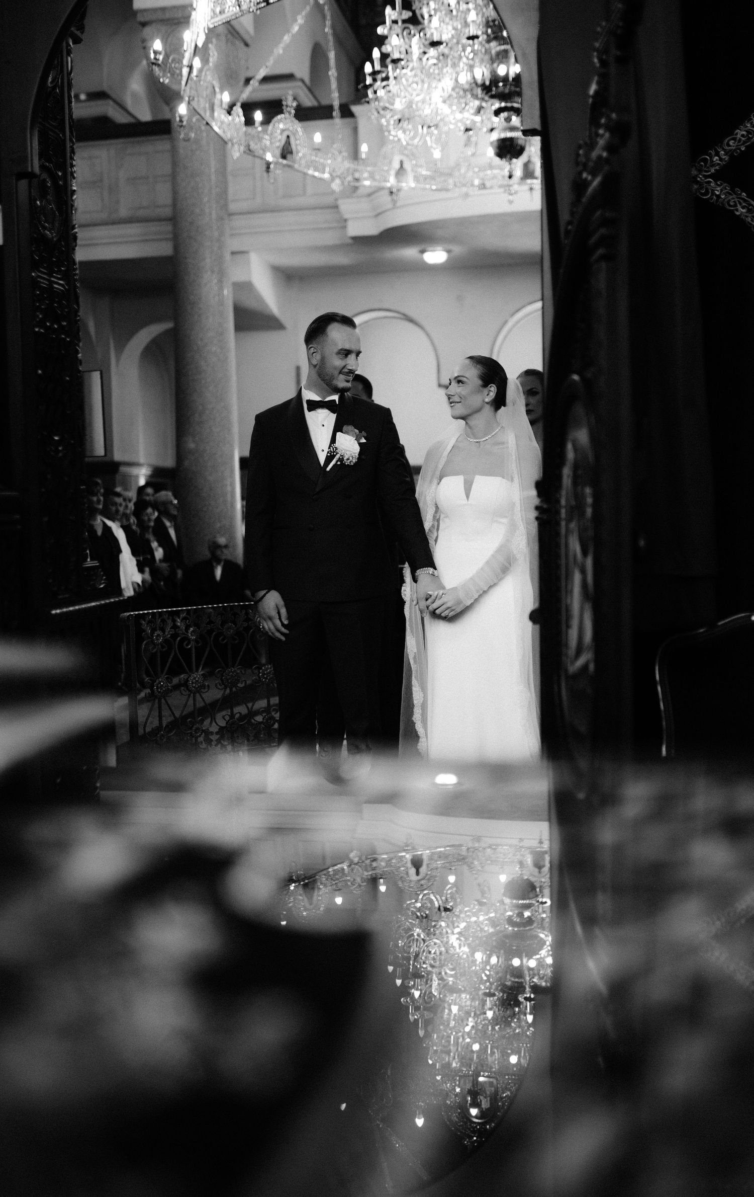 A black and white wedding photo montage showing a couple dancing in an elegant ballroom with chandeliers.