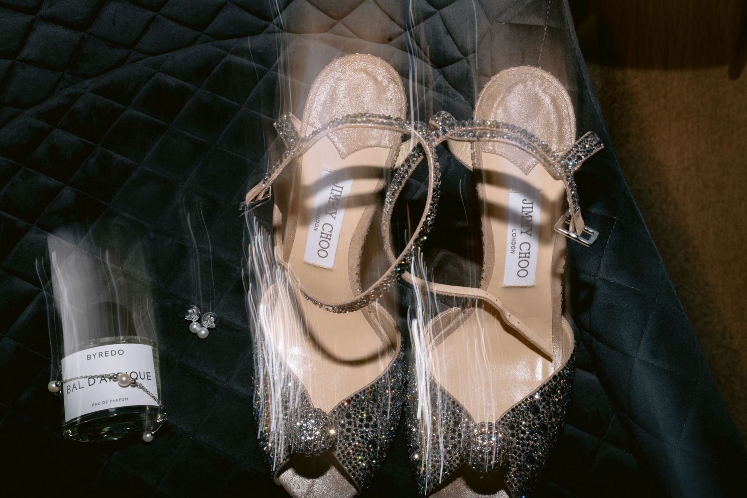 Close-up detail shot of sparkly bridal shoes against dark background.