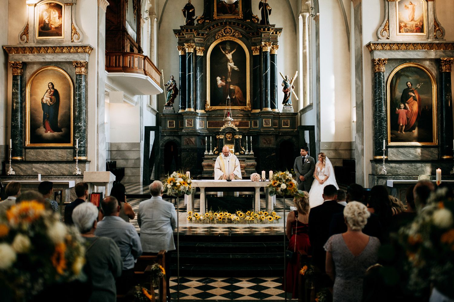 Traditional church wedding ceremony with ornate altar and religious artwork.