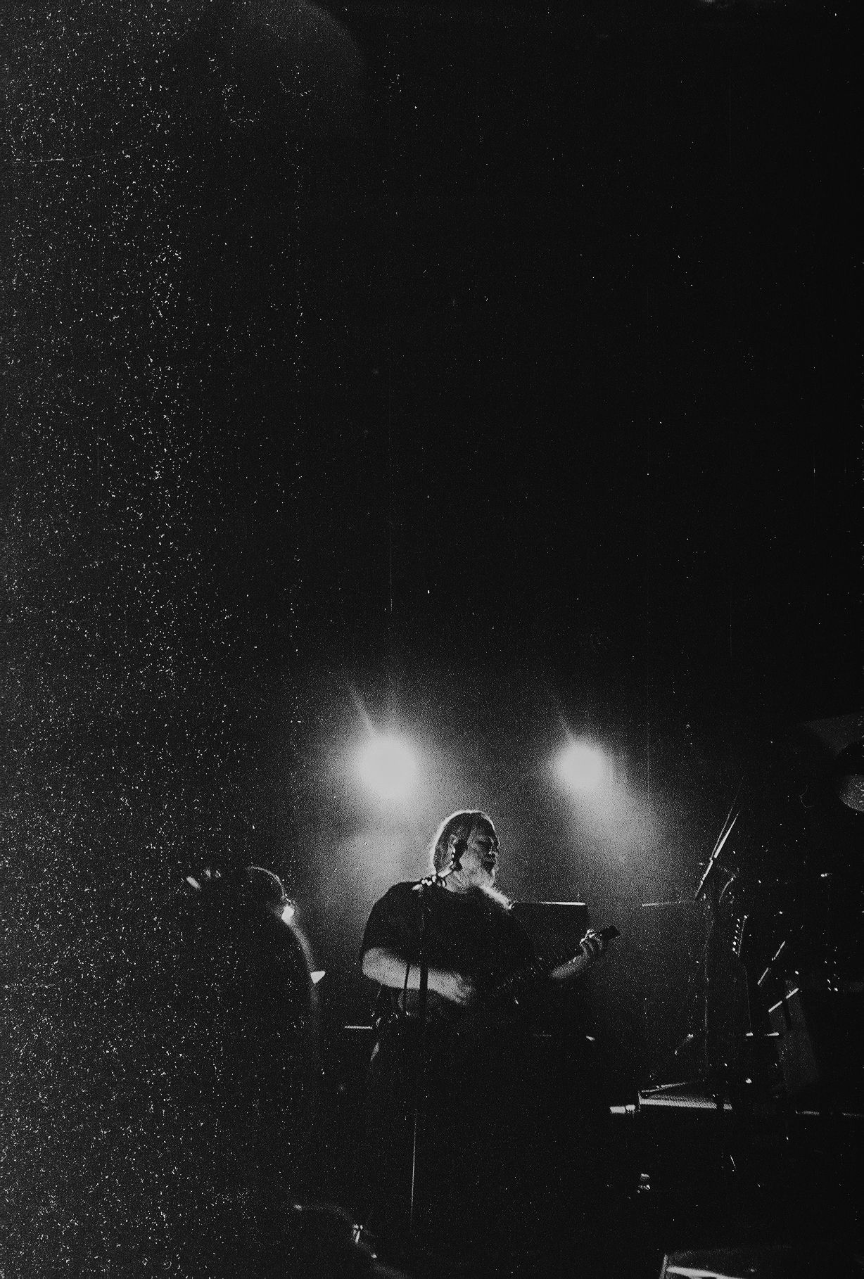 Silhouetted performers on a dark stage with dramatic backlighting creating an atmospheric concert scene.