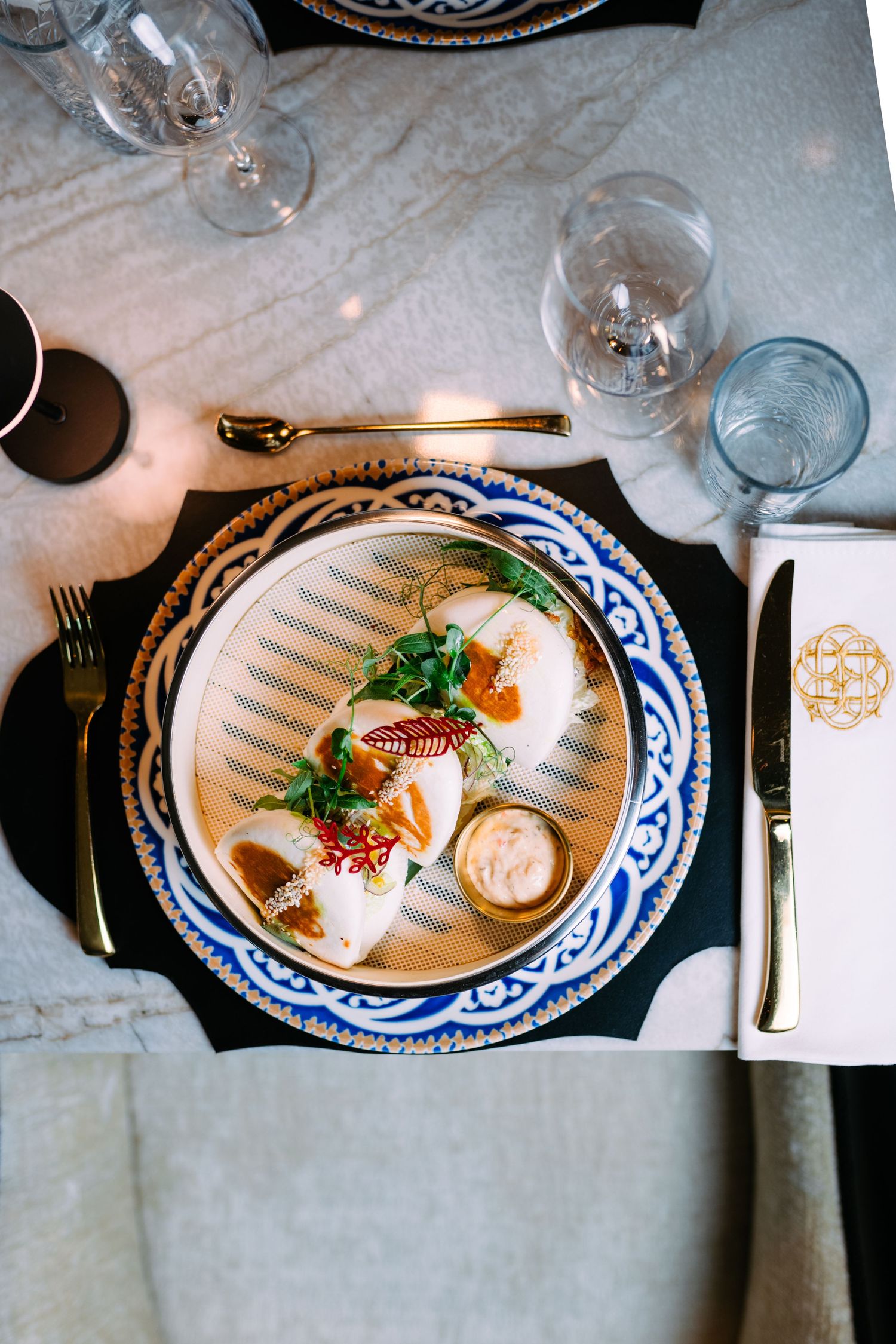 Elegant table setting with blue and white china plates and wine glasses arranged in a fine dining presentation.